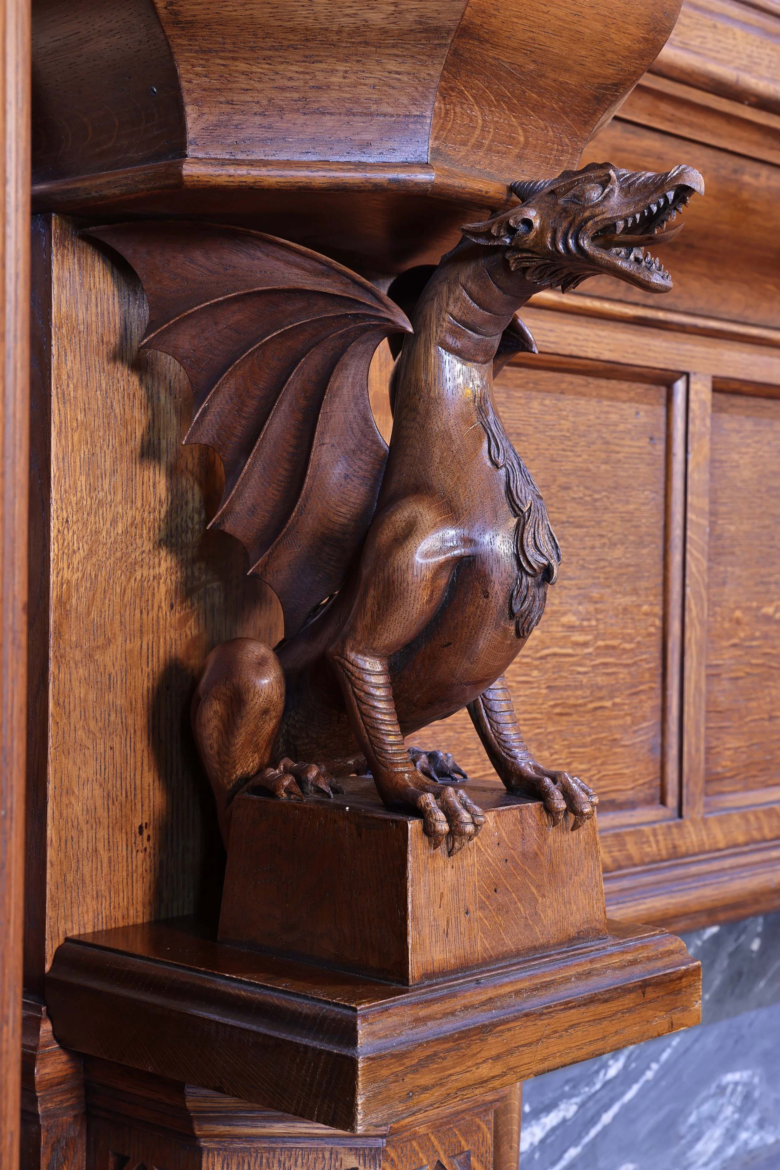 Close up of hand carved oak dragon, Gothic style fireplace decoration, detailed architectural wood carving.