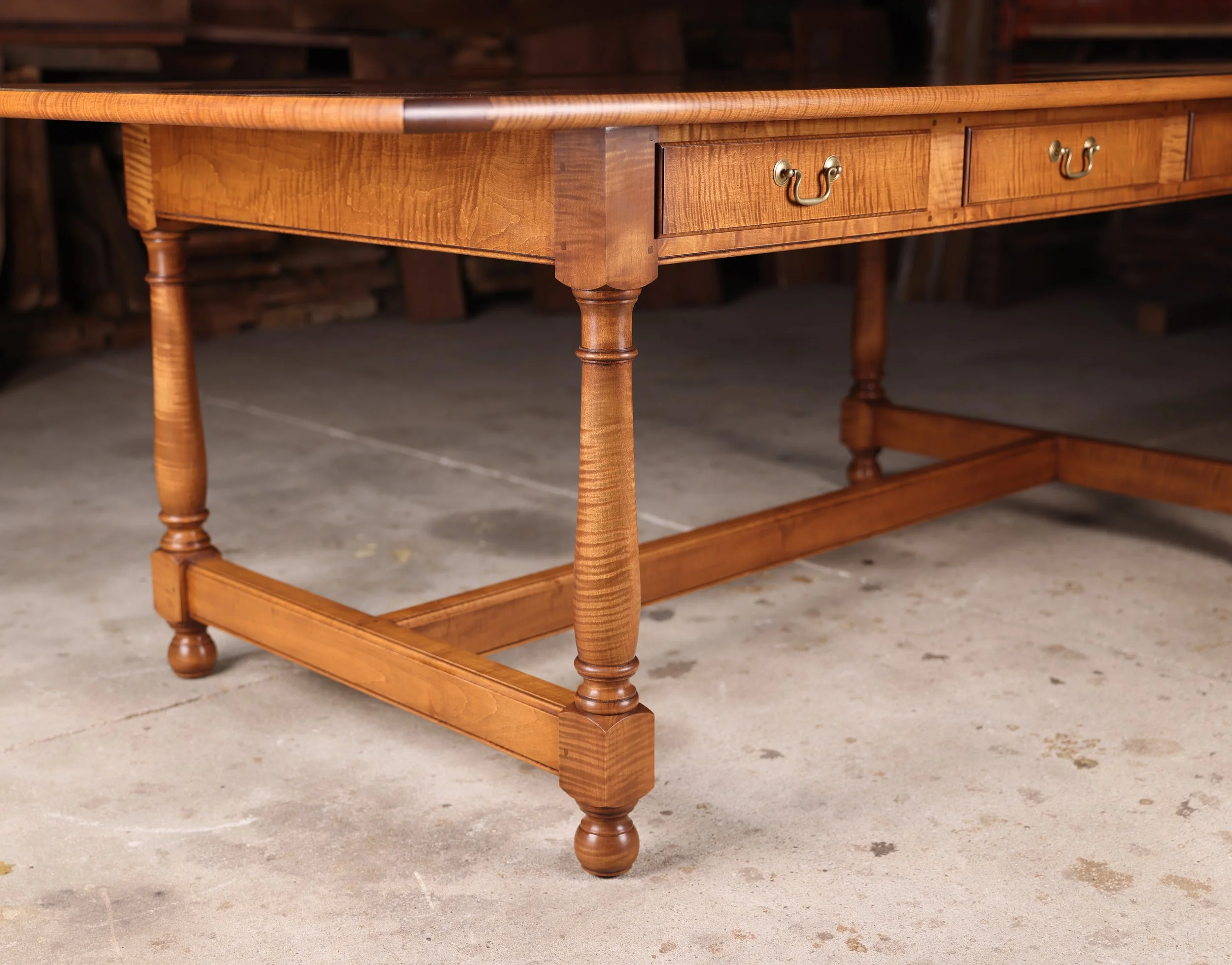 Bespoke tiger maple dining room table  showing hand turned legs with hand cut dovetailed drawers.