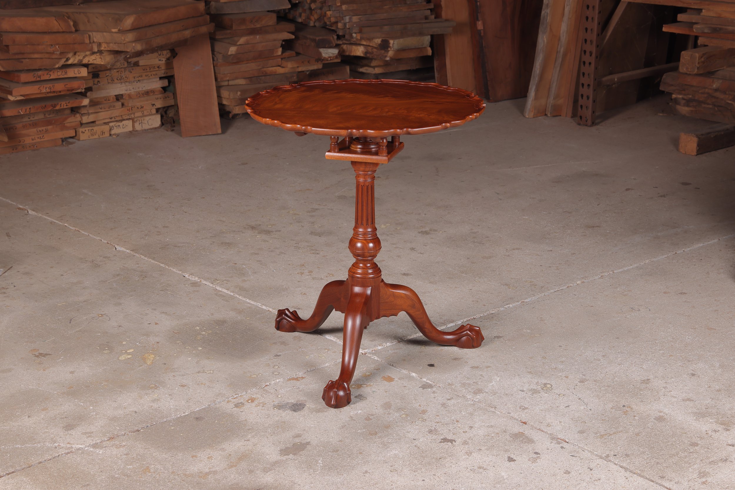 A solid walnut Philadelphia piecrust tea table built by Irion Company Furniture Makers featuring a highly figured crotch wood top and hand carved ball and claw feet