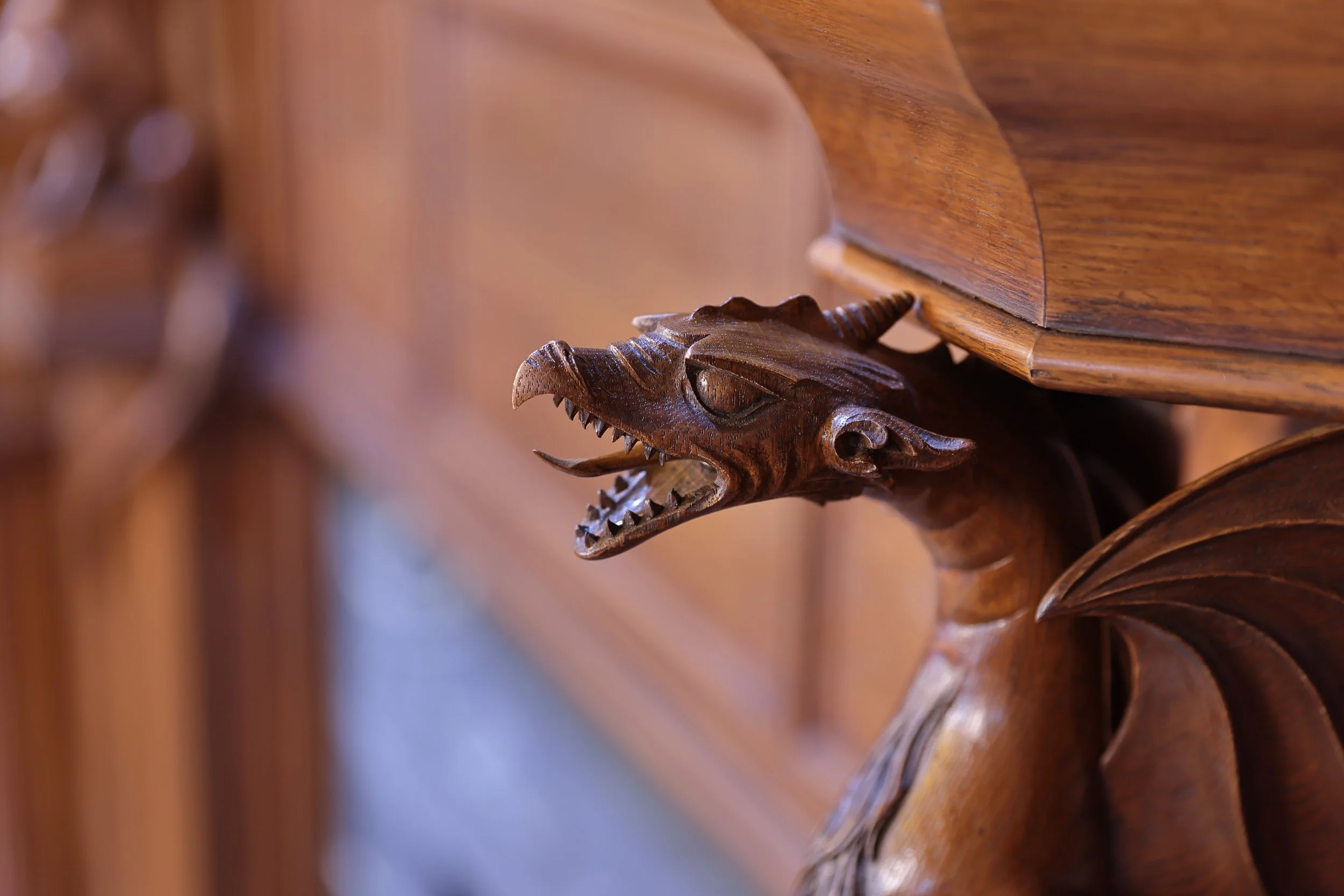 Close up of hand carved oak dragon, Gothic style fireplace decoration, detailed architectural wood carving.