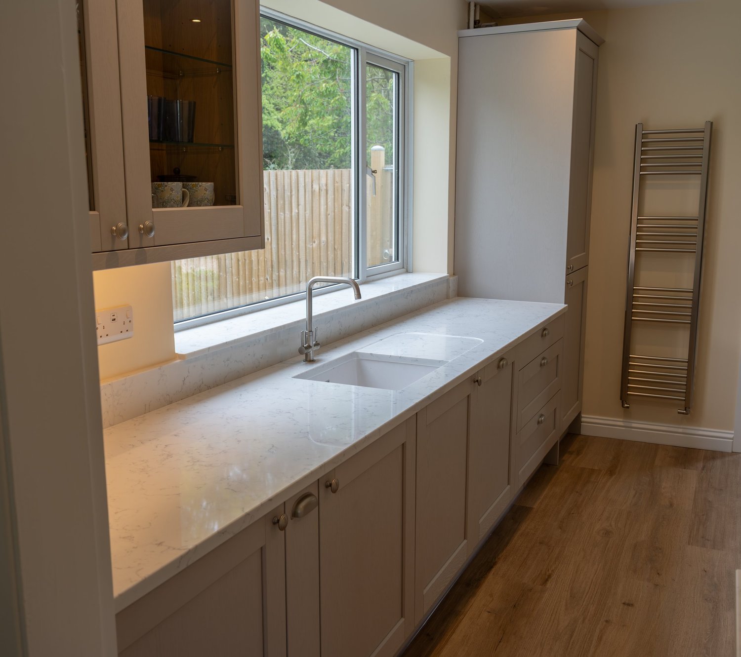 Cashmere Shaker sink run with a quartz worktop beside the garden window, Thakeham