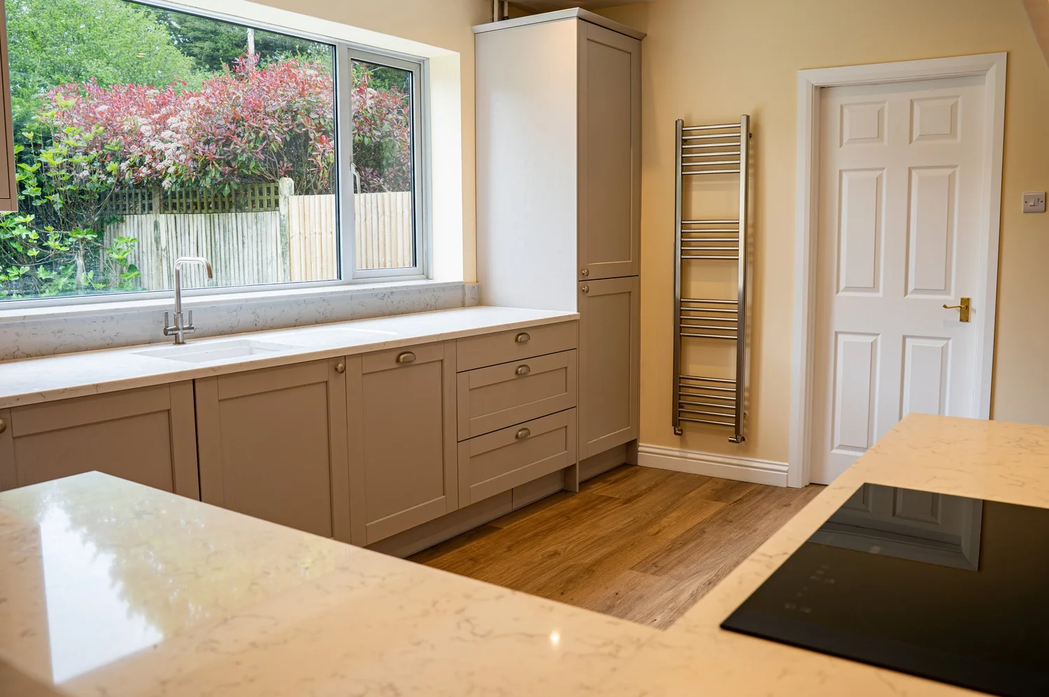 Cashmere Shaker kitchen with quartz worktops and a garden view in Thakeham