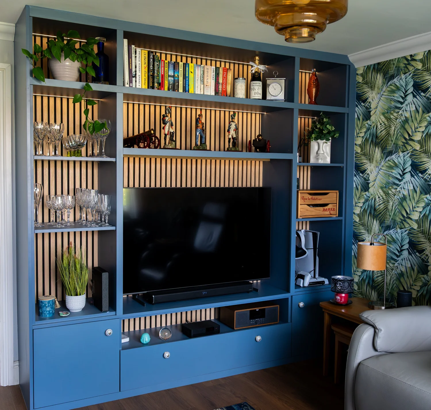 Misty blue media wall with oak acoustic panelling, open shelves and a television in a Lancing living room