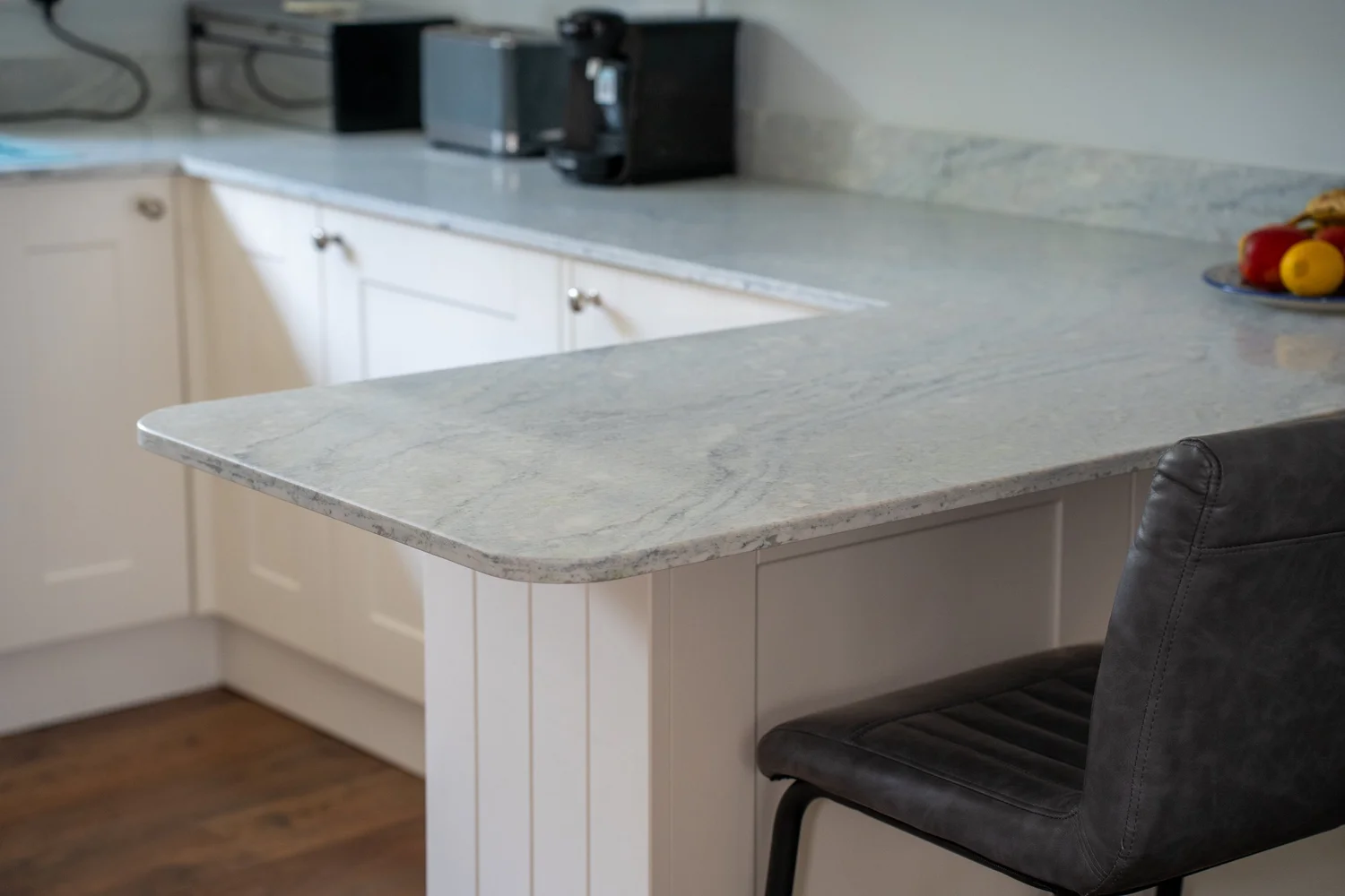 Pacific Blue quartz worktop on a cream peninsula with a bar stool, Storrington