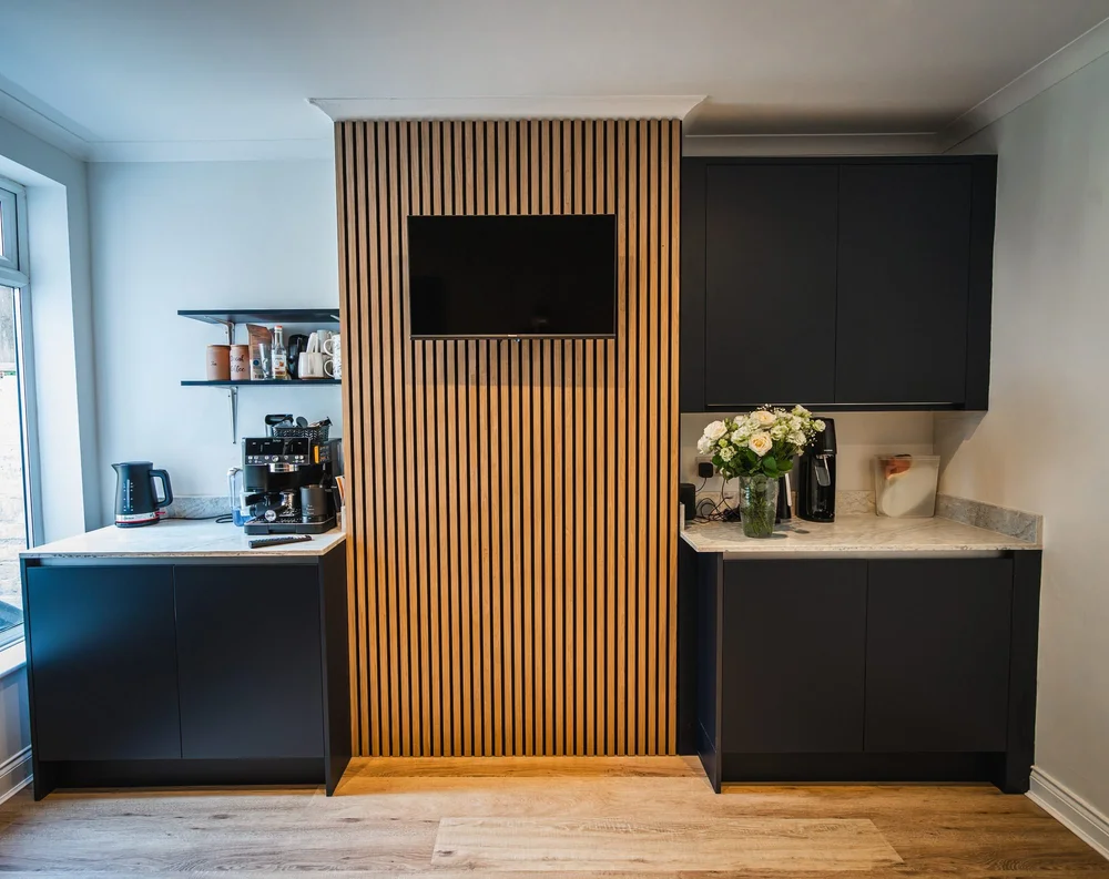 TV on oak slats with indigo cupboards each side, seen as you come into a Bognor Regis kitchen