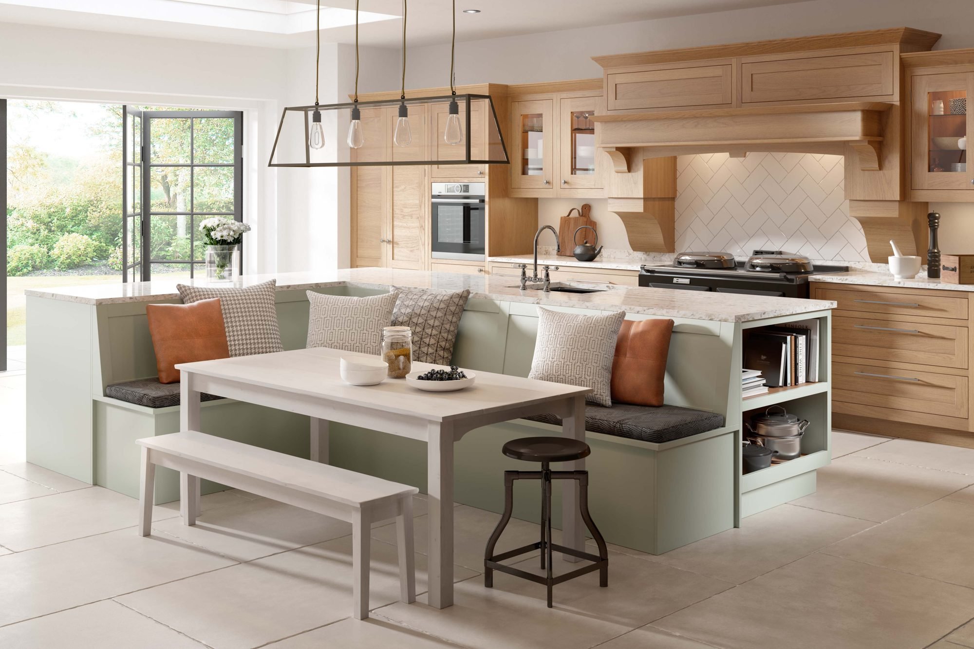 Kitchen with an oak topped island, built in bench seating in soft green and a table beside it, with garden doors behind
