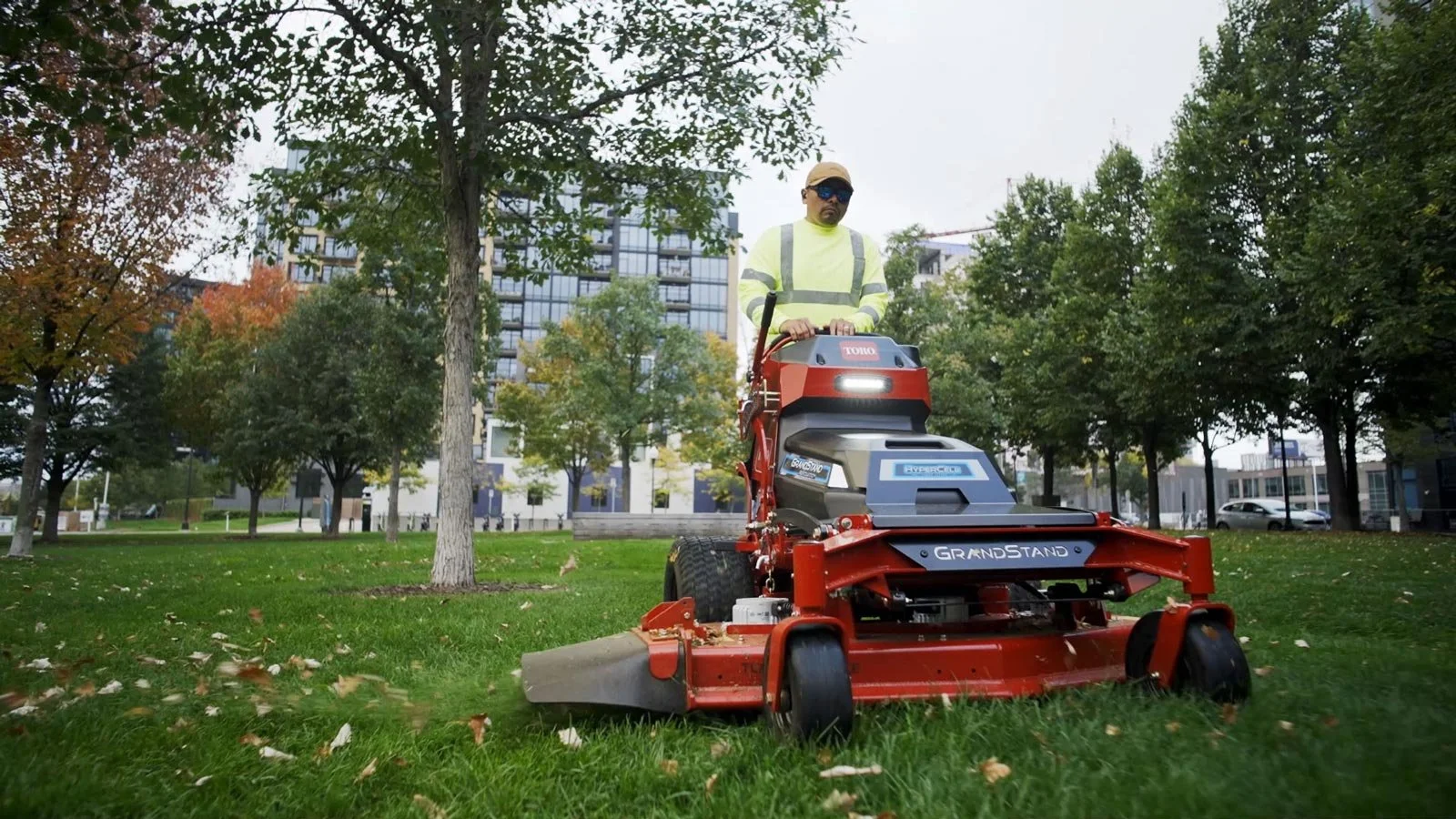 A person pushing a black and yellow push lawn mower on a grassy lawn.