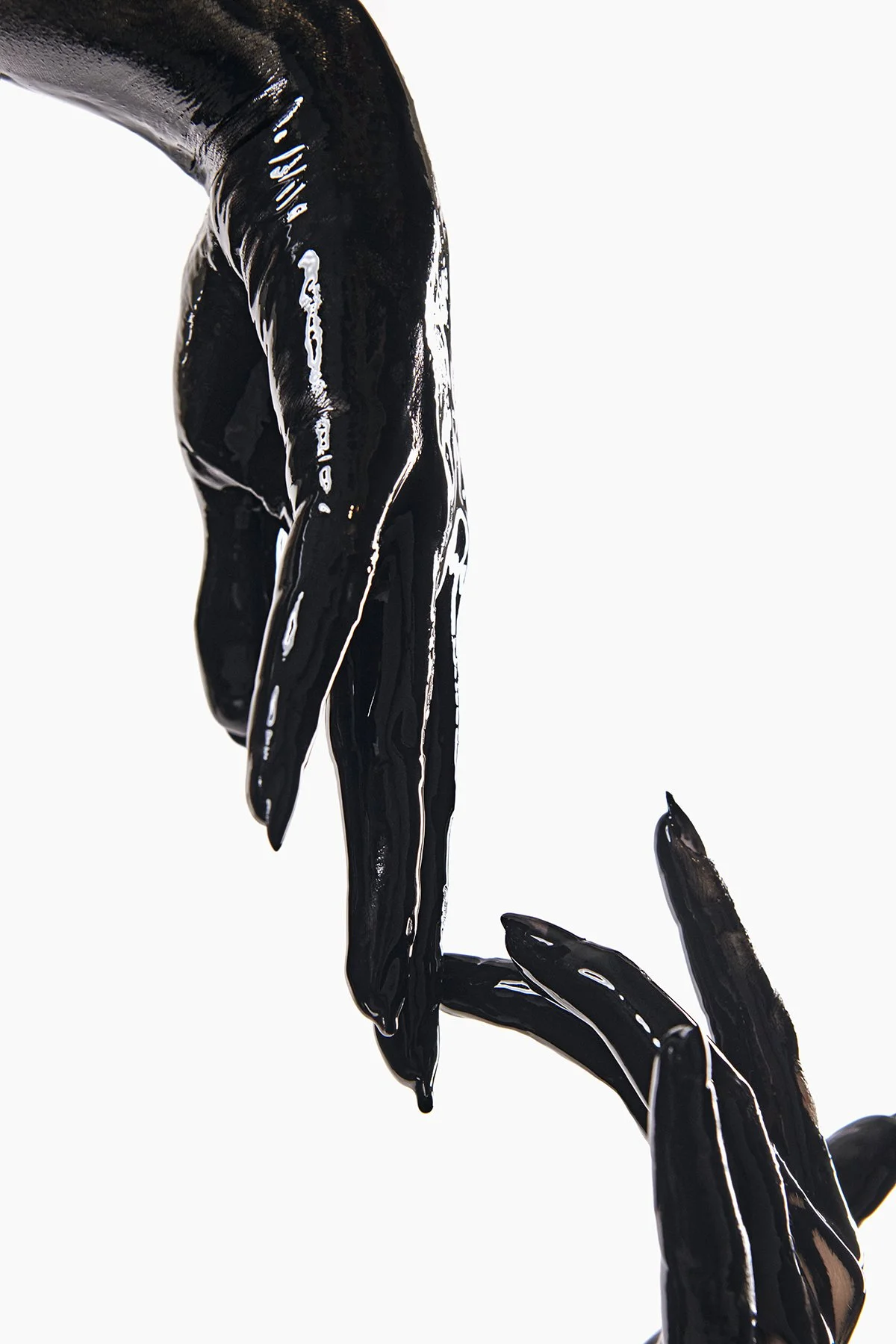 Two black, glossy, elongated hands or fingers delicately touching against a bright white background. paint it black shakira la tortura inspired shoot black paint model nude covered in paint full body paint toronto makeup artist sensual editorial 