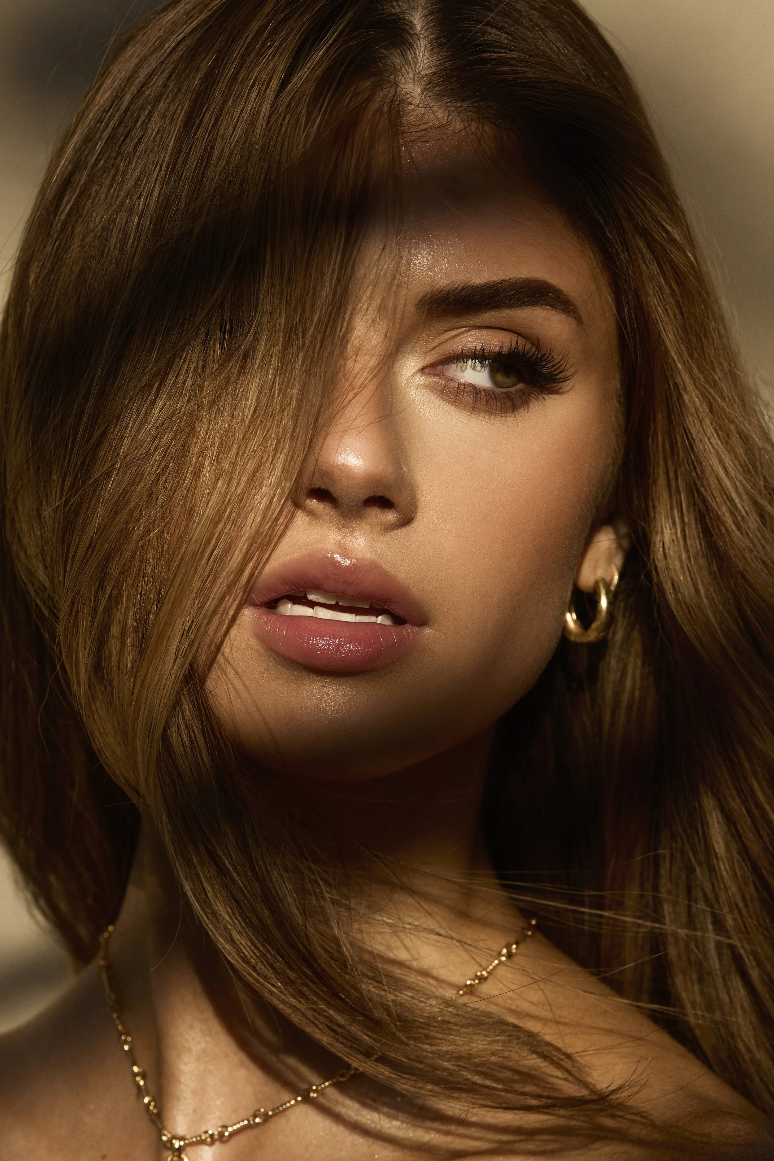 A woman with long, voluminous chestnut hair, looking slightly to the side with her eye partially covered by her hair. Los angeles creative editorial photoshoot commercial beauty campaign fenty sephora toronto mua abanian 