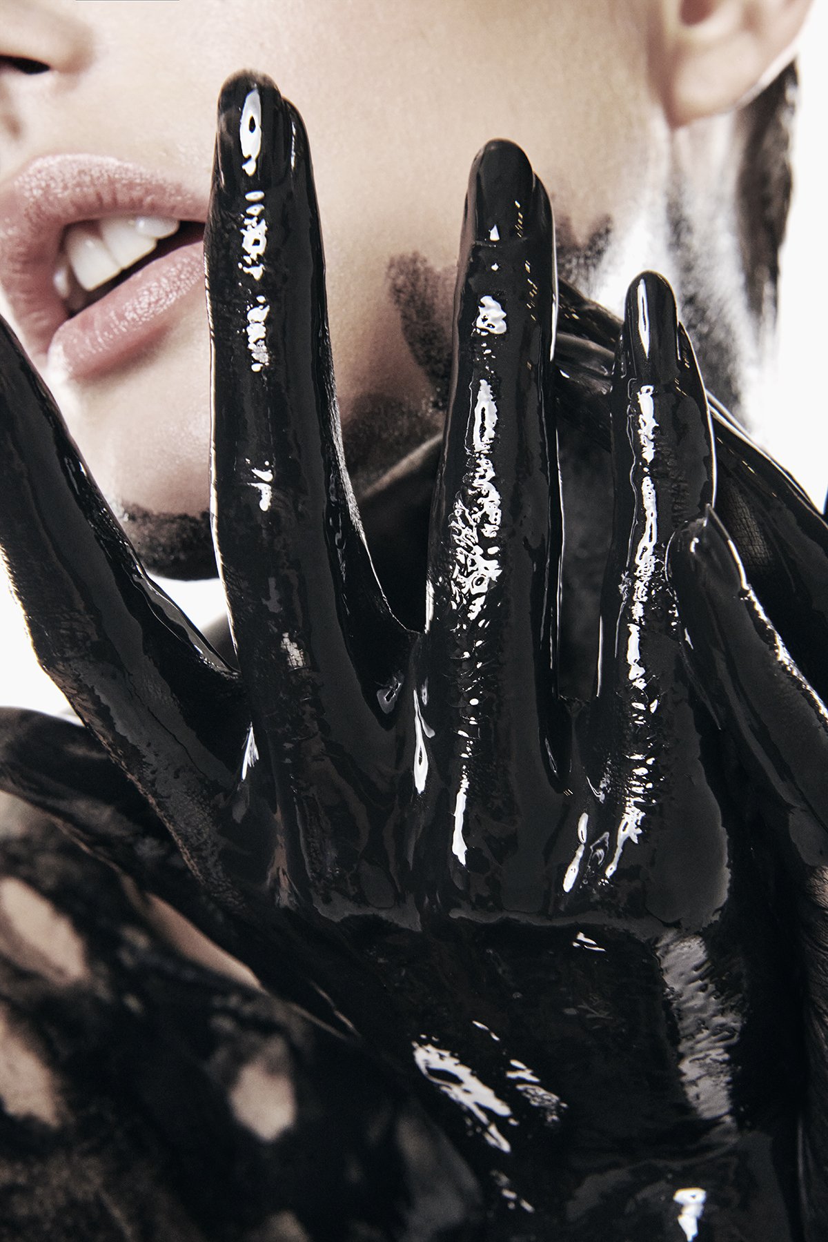 Close-up of a woman's face and lips, partially visible, with a hand covered in shiny black paint raised near her lips.
Toroto editorial shoot inspired by shakira la tortura black paint full body paint shiny glossy avant garde 