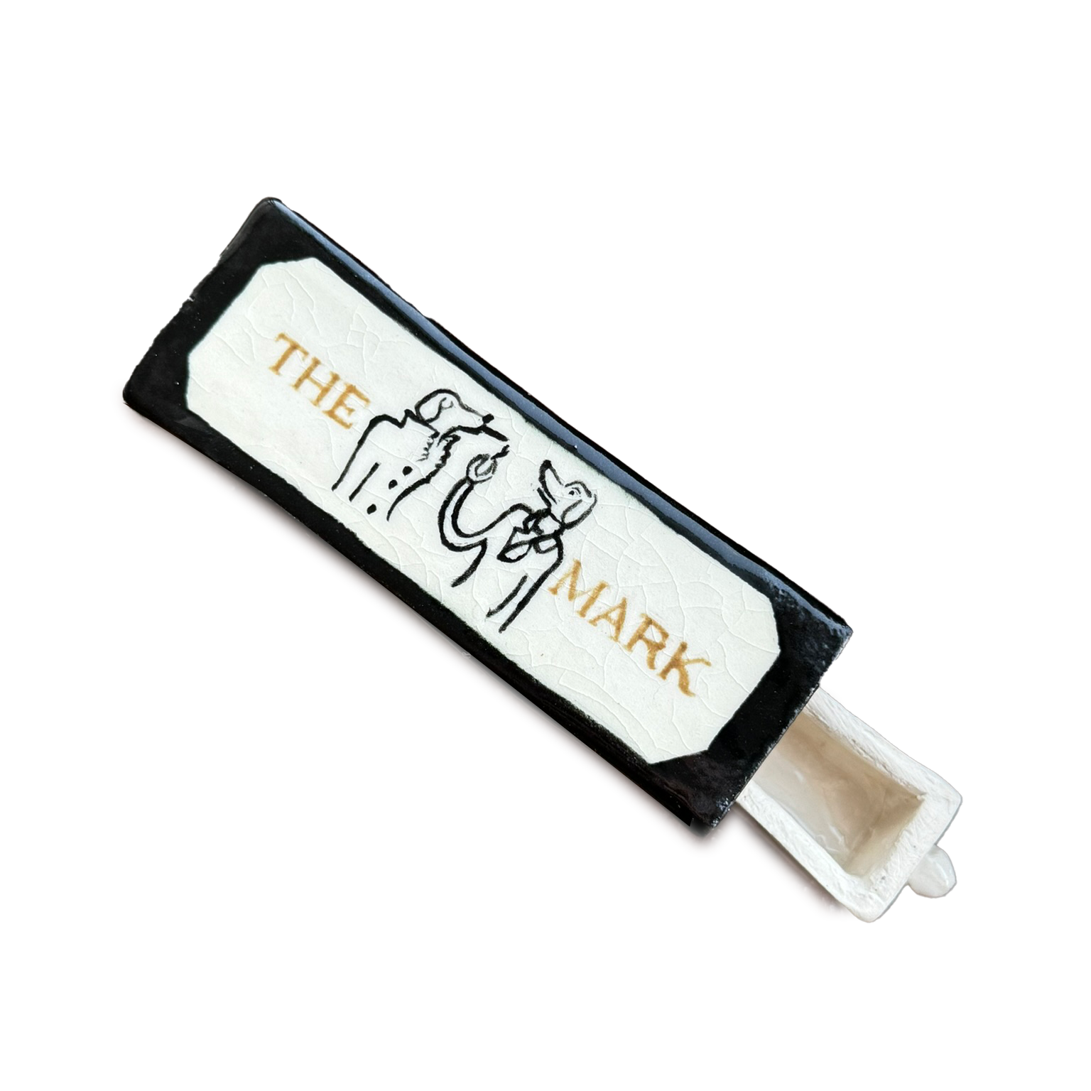 A matchbox with the words "The Marl" and a drawing of a lion and a house on it, with an unlit matchstick placed inside.
