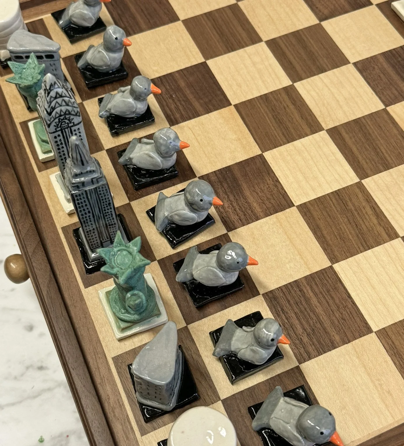 A chessboard with ceramic chess pieces, including pawns, rooks, and bishops, designed as ducks and other figures.