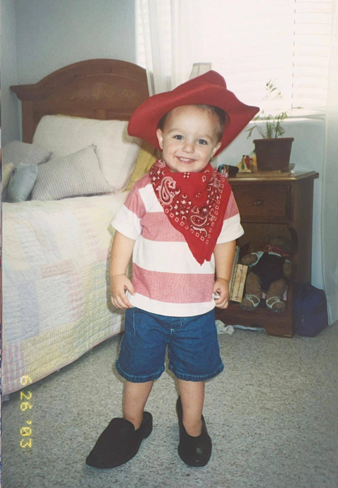 Young Andrew in a cowboy hat and one loafer and one heel.