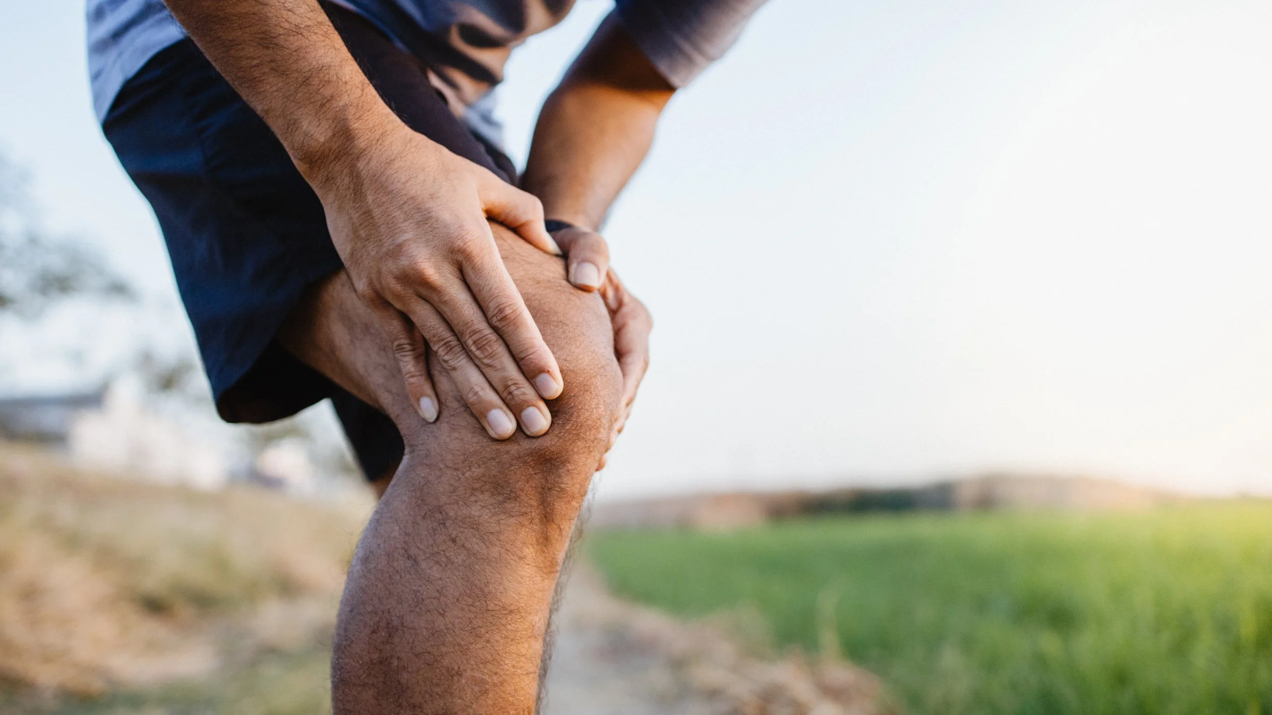 Sporty man in pain after sustaining a knee sprain or strain during a running training session