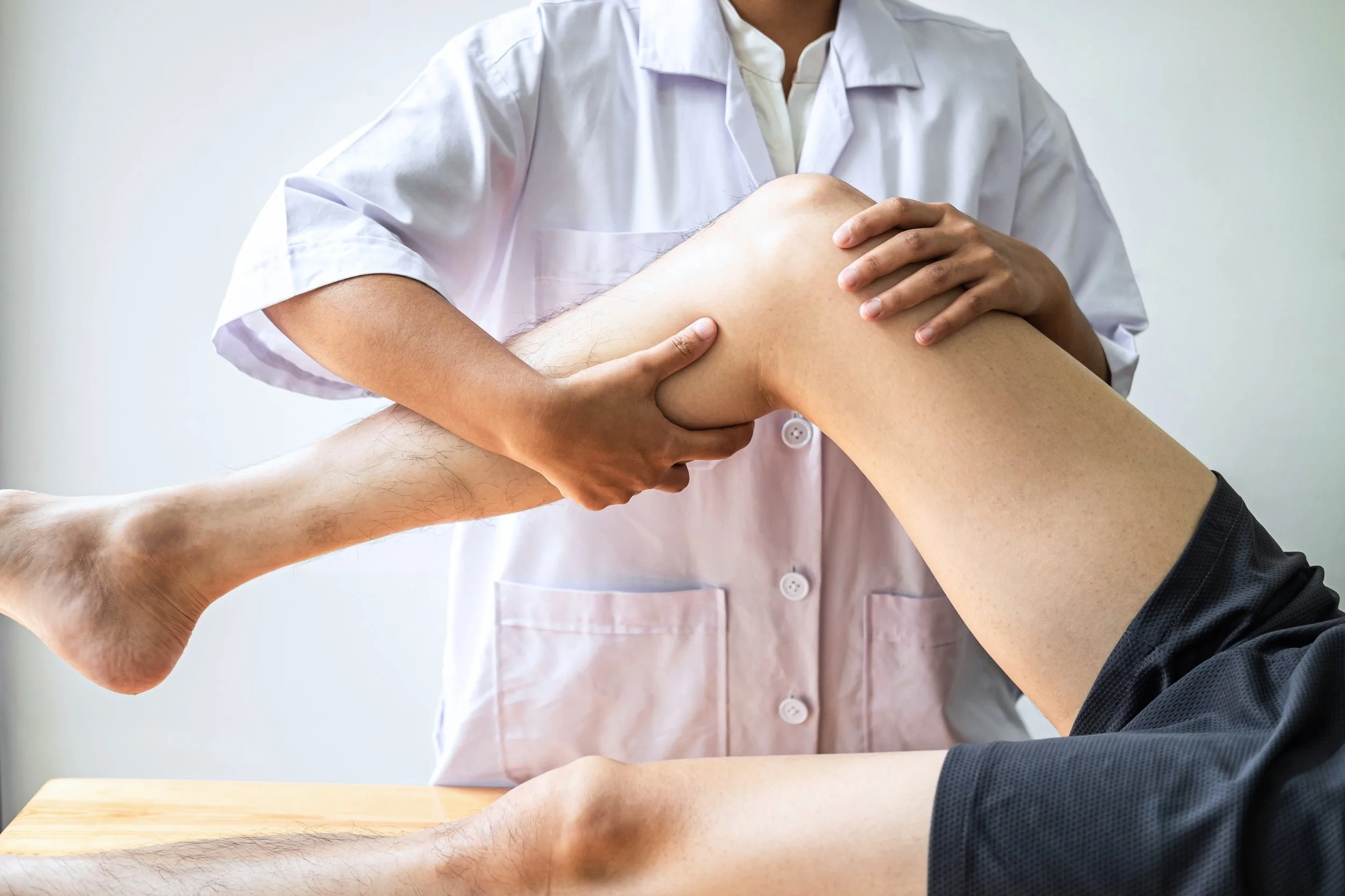Female Physiotherapist working examining treating LCL tear of male patient, Doing exercises the Rehabilitation therapy pain in clinic