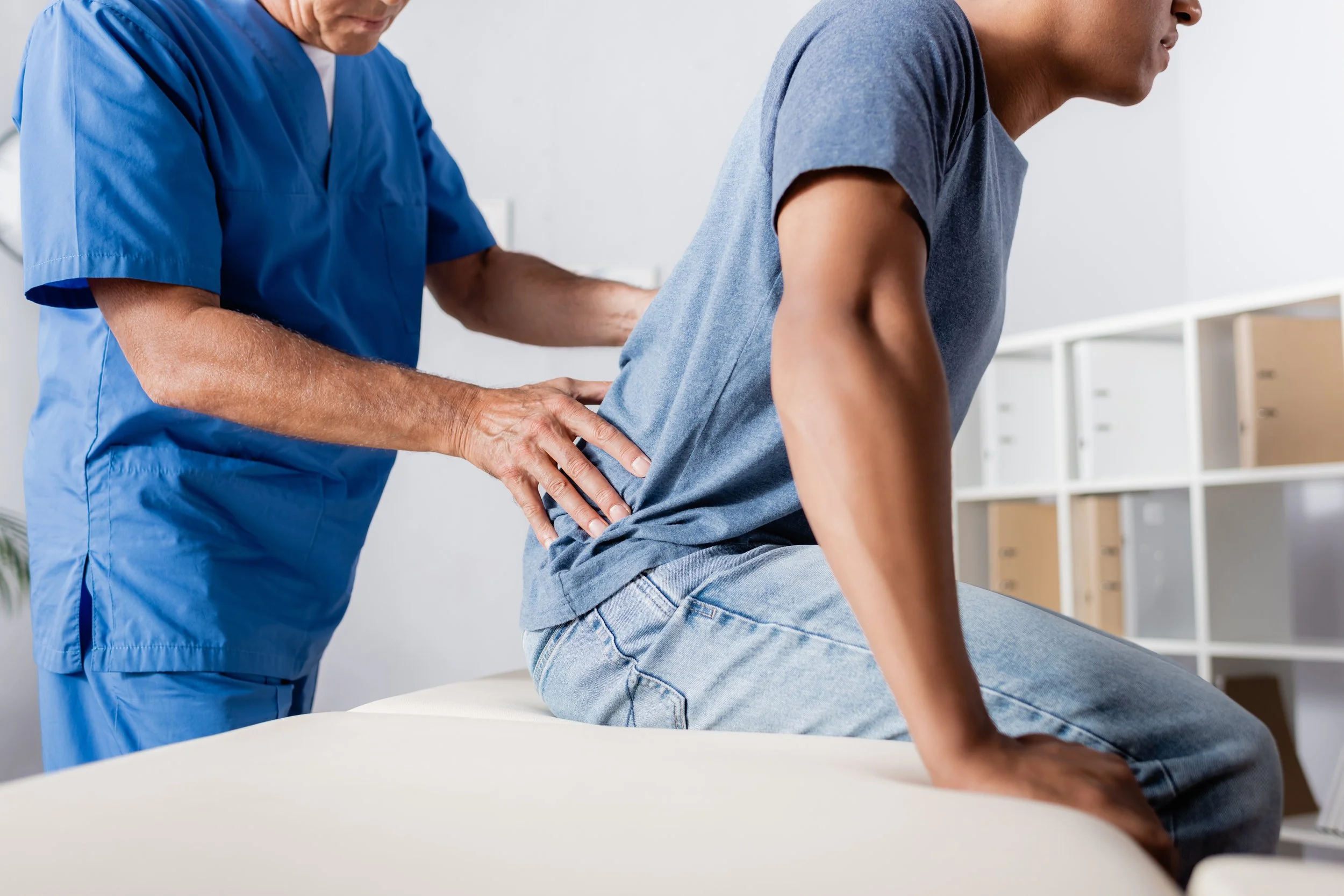 cropped view of physiotherapist assessing lower back of man