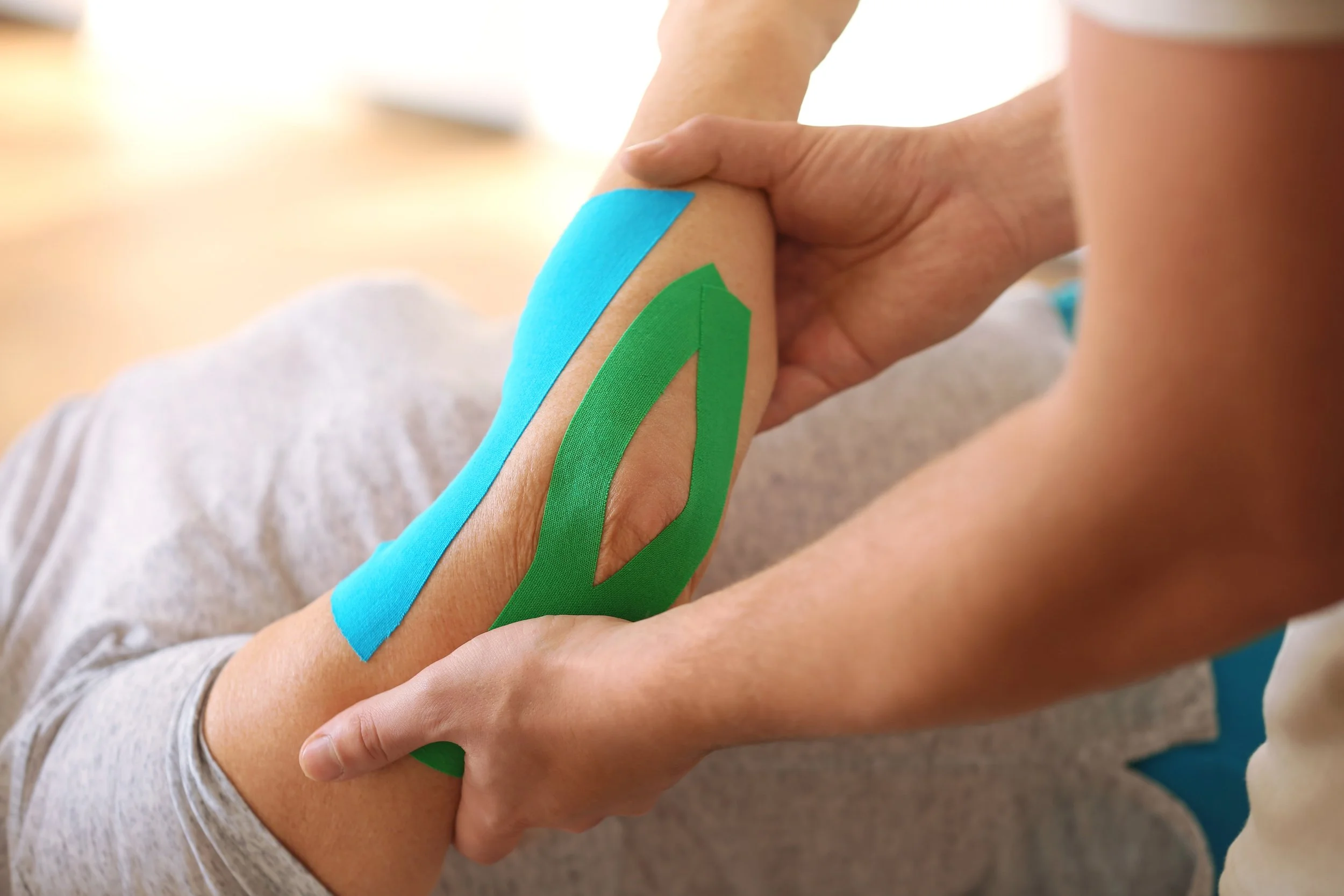 Physiotherapist working with elderly patient in clinic, closeup, kinesio taping