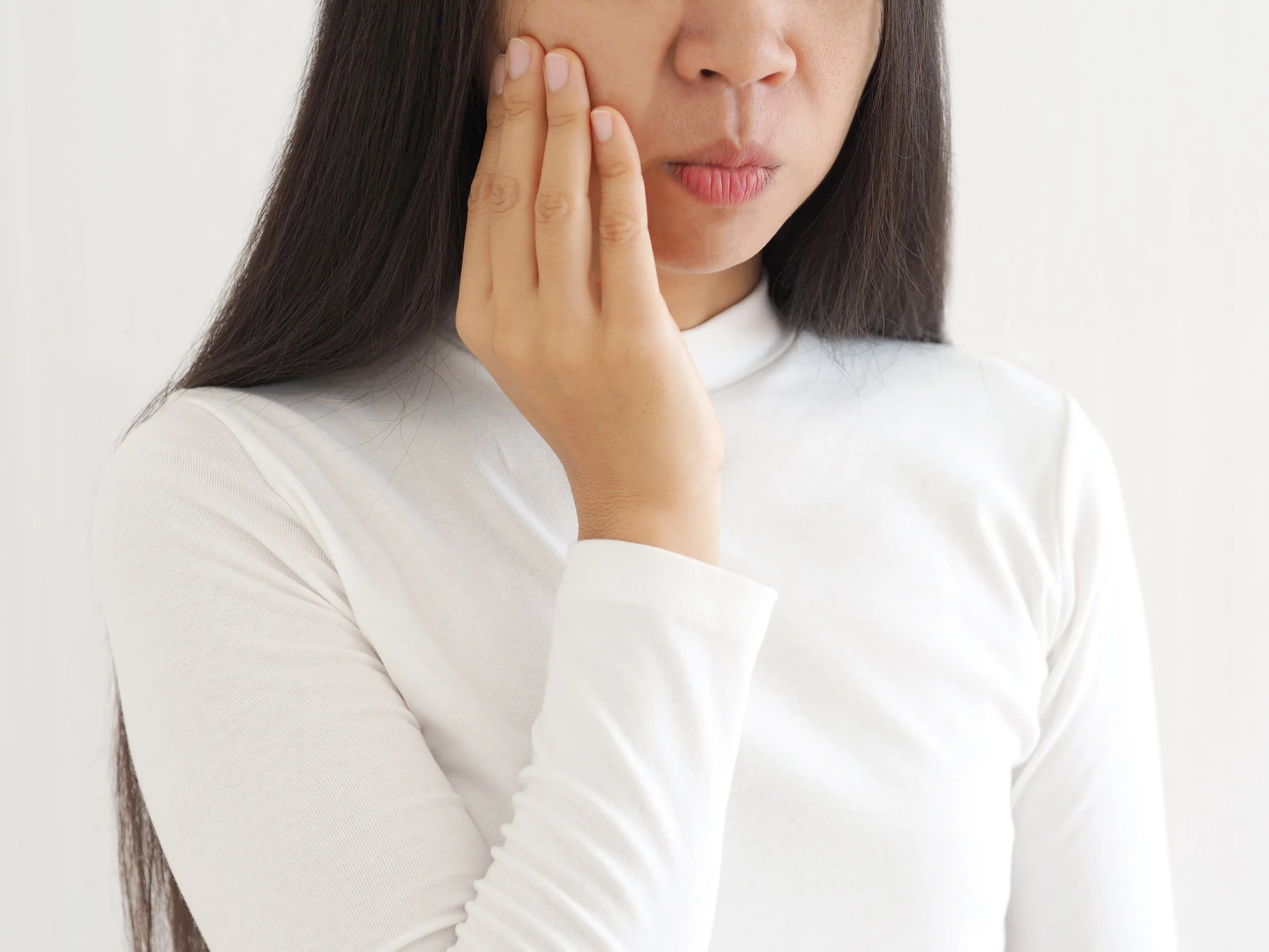 trigeminal neuralgia and temporomandibular joint and muscle disorder in asian woman, She use hand touching her cheek and symptoms fo pain and suffering on isolated white background.