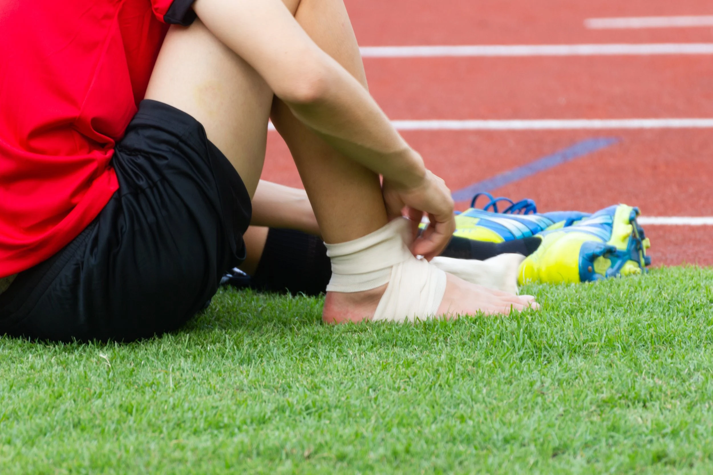 Male athlete applying compression bandage onto ankle sprain strain of a soccer player, Sports injuries