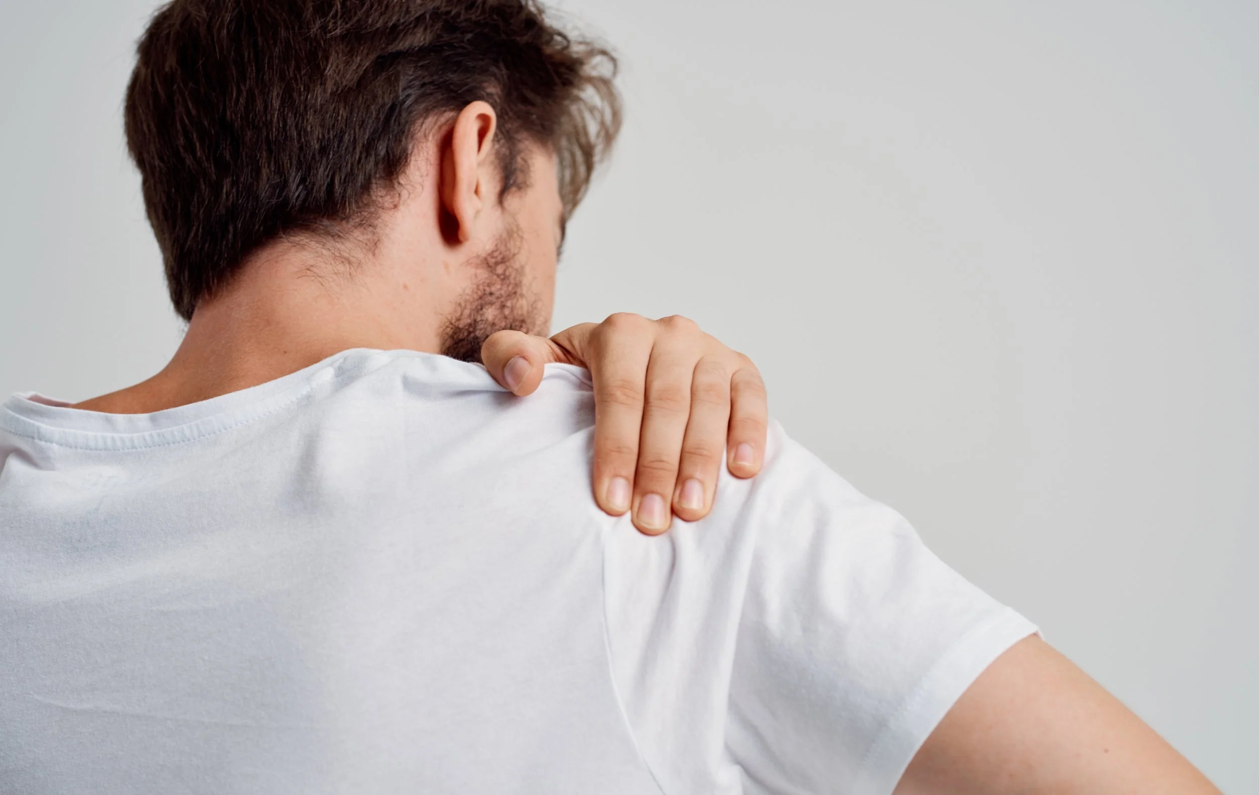 bearded man touching shoulder with hand pain dislocation medical intervention