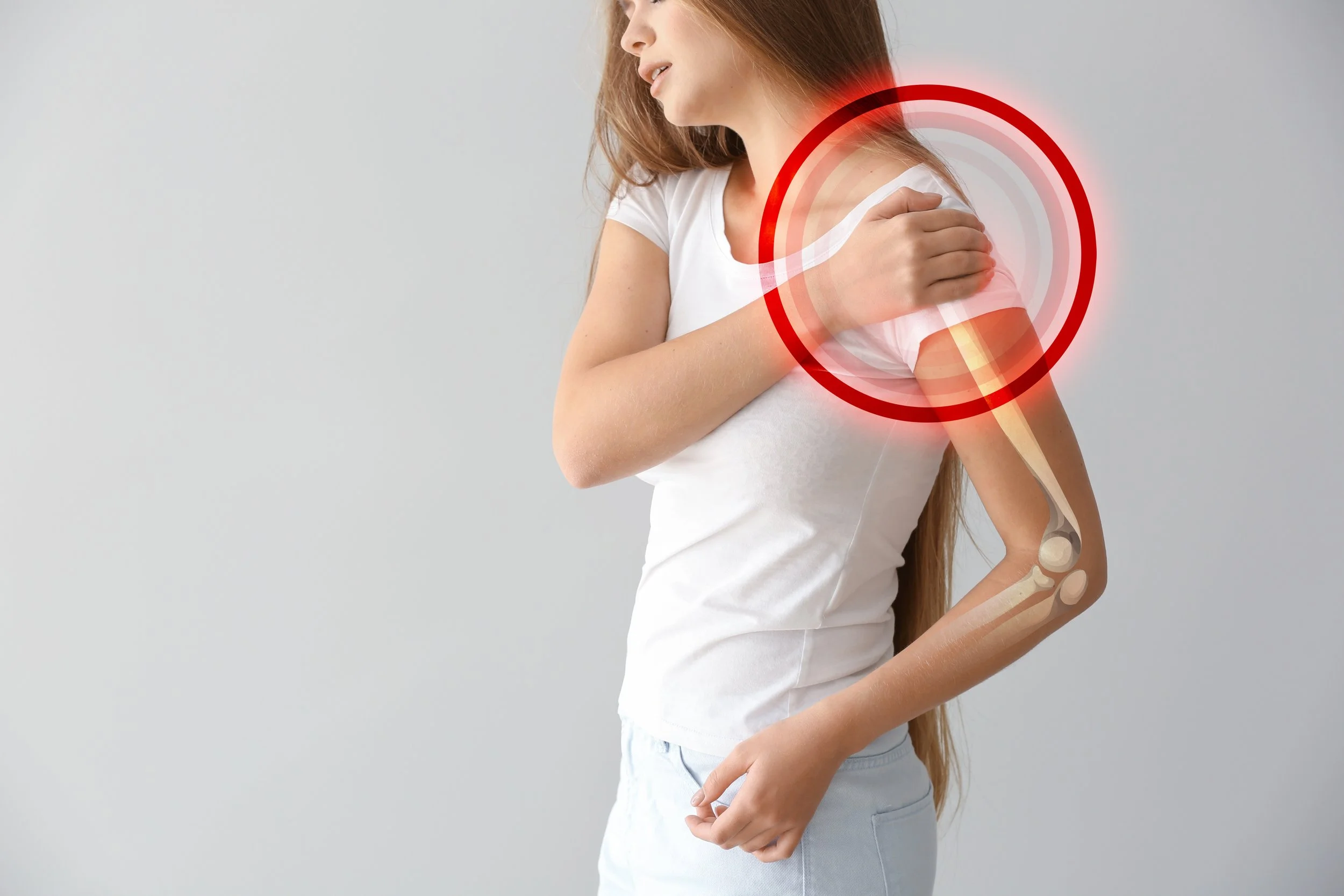 Young woman with pain in shoulder on light background