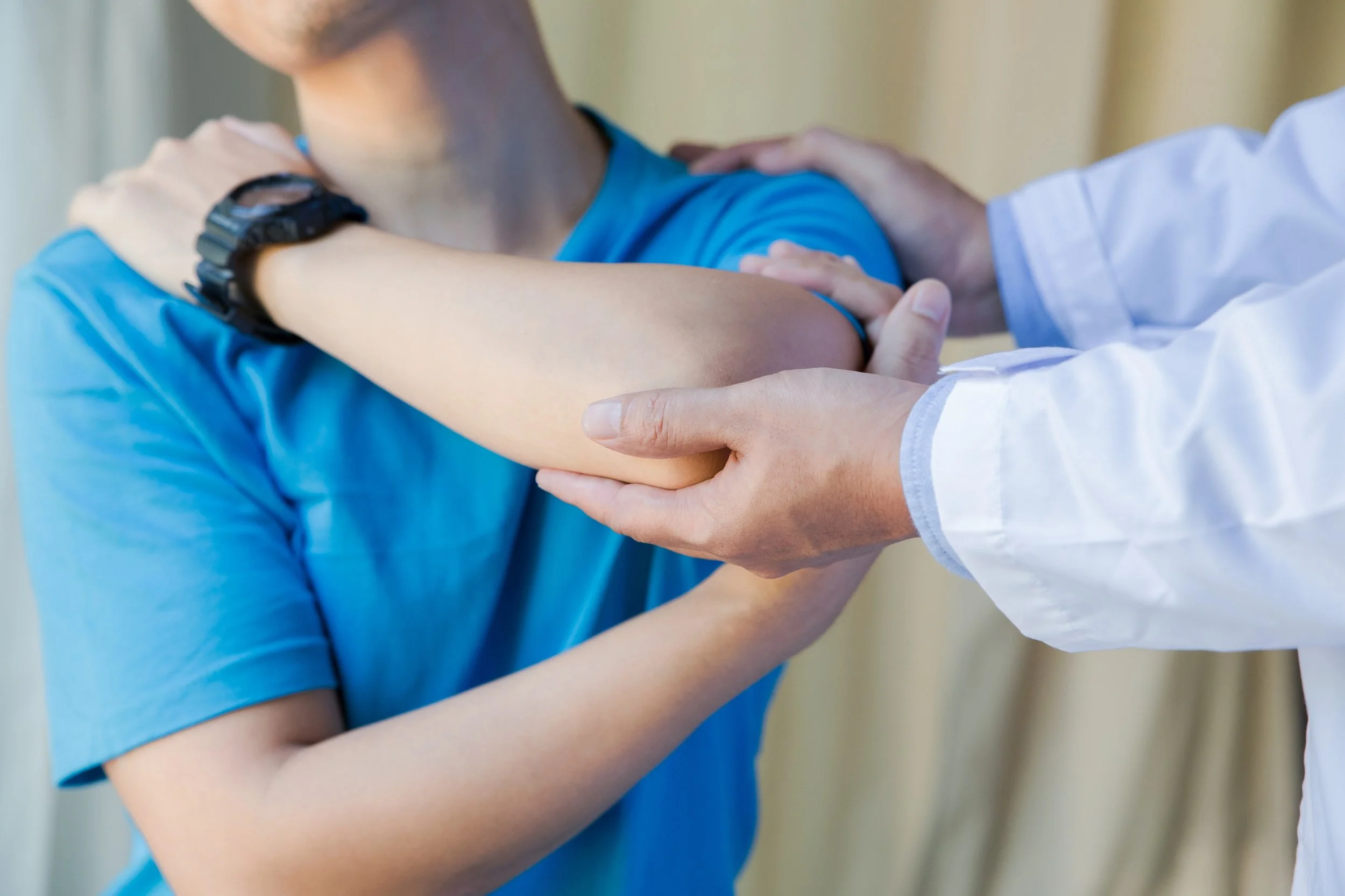 muscular man with shoulder ache exercising with physiotherapist