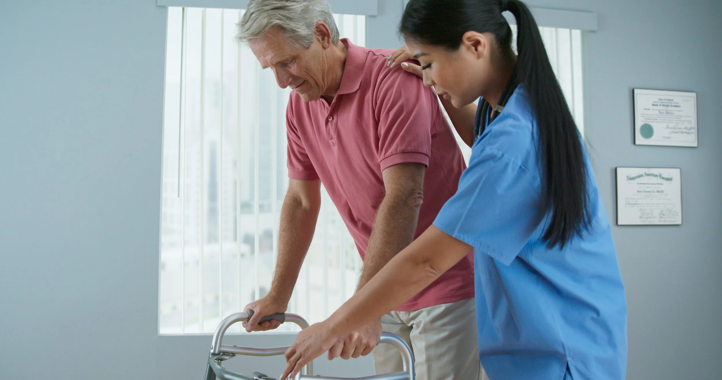 Senior male patient learning to use walker with the assistance of female physical therapist or nurse. Doctor helping older man walk again in recovery