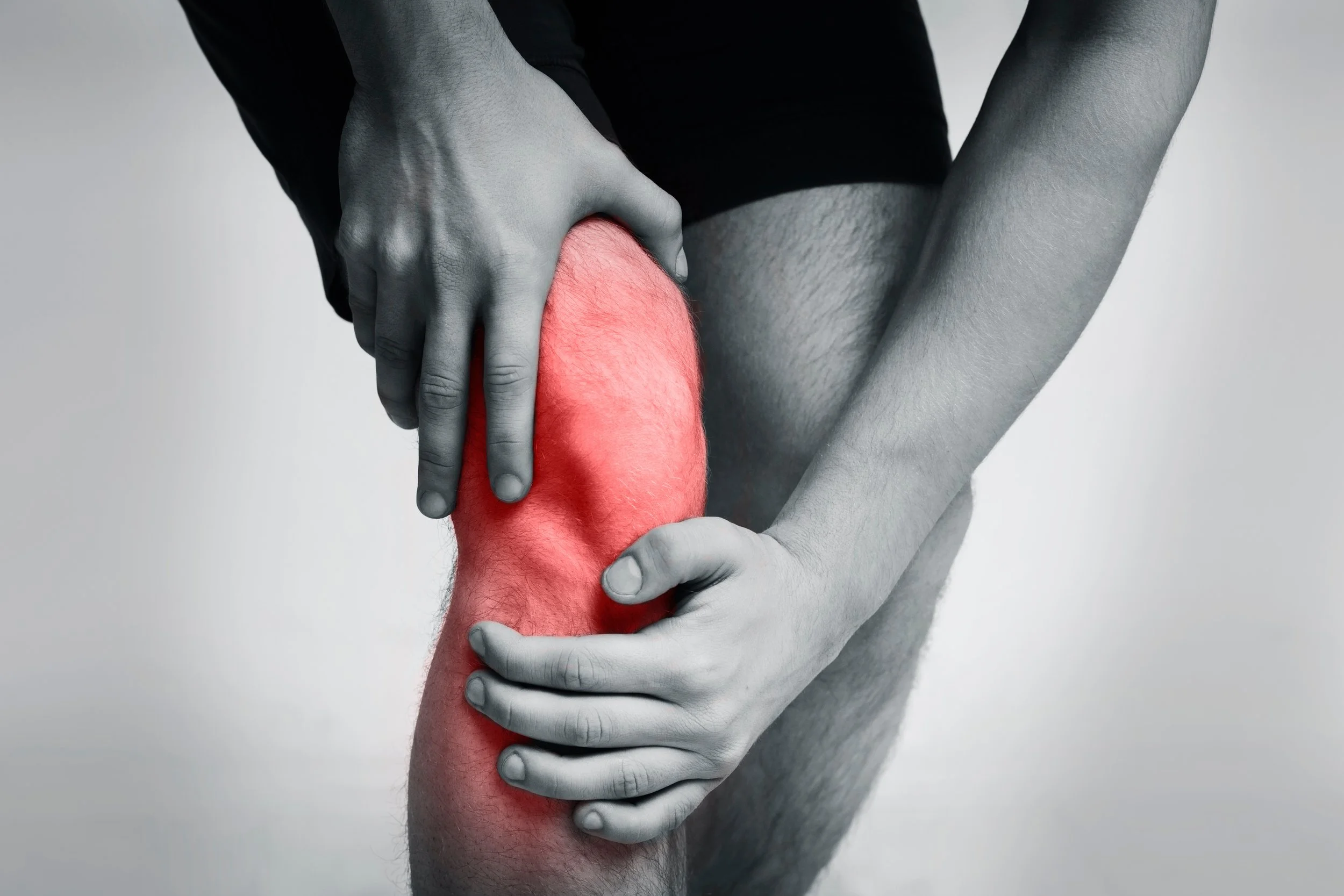 Person holding knee in pain, with area highlighted in red, indicating discomfort or injury.