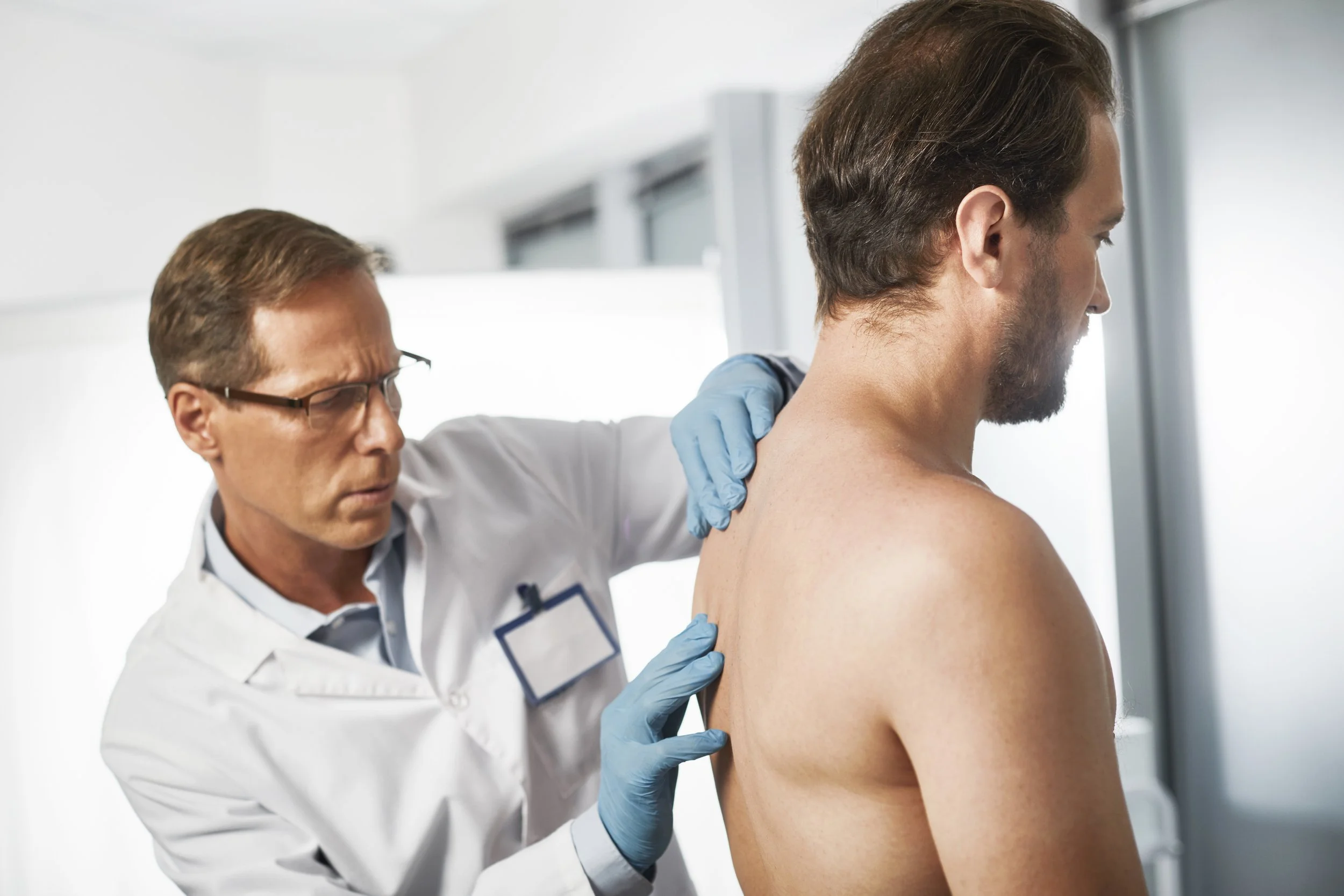 Waist up portrait of male medic exploring middle back thoracic spine to excluding various diseases