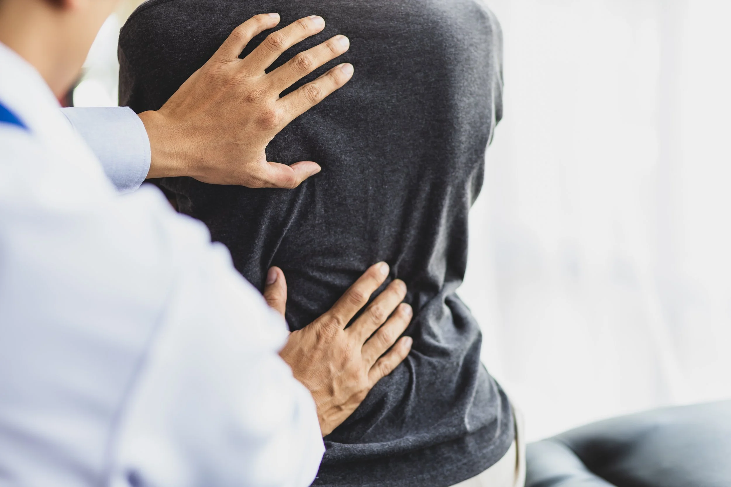 Physiotherapist examining woman's hip who is suffering from trochanteric bursitis in examination room in clinic