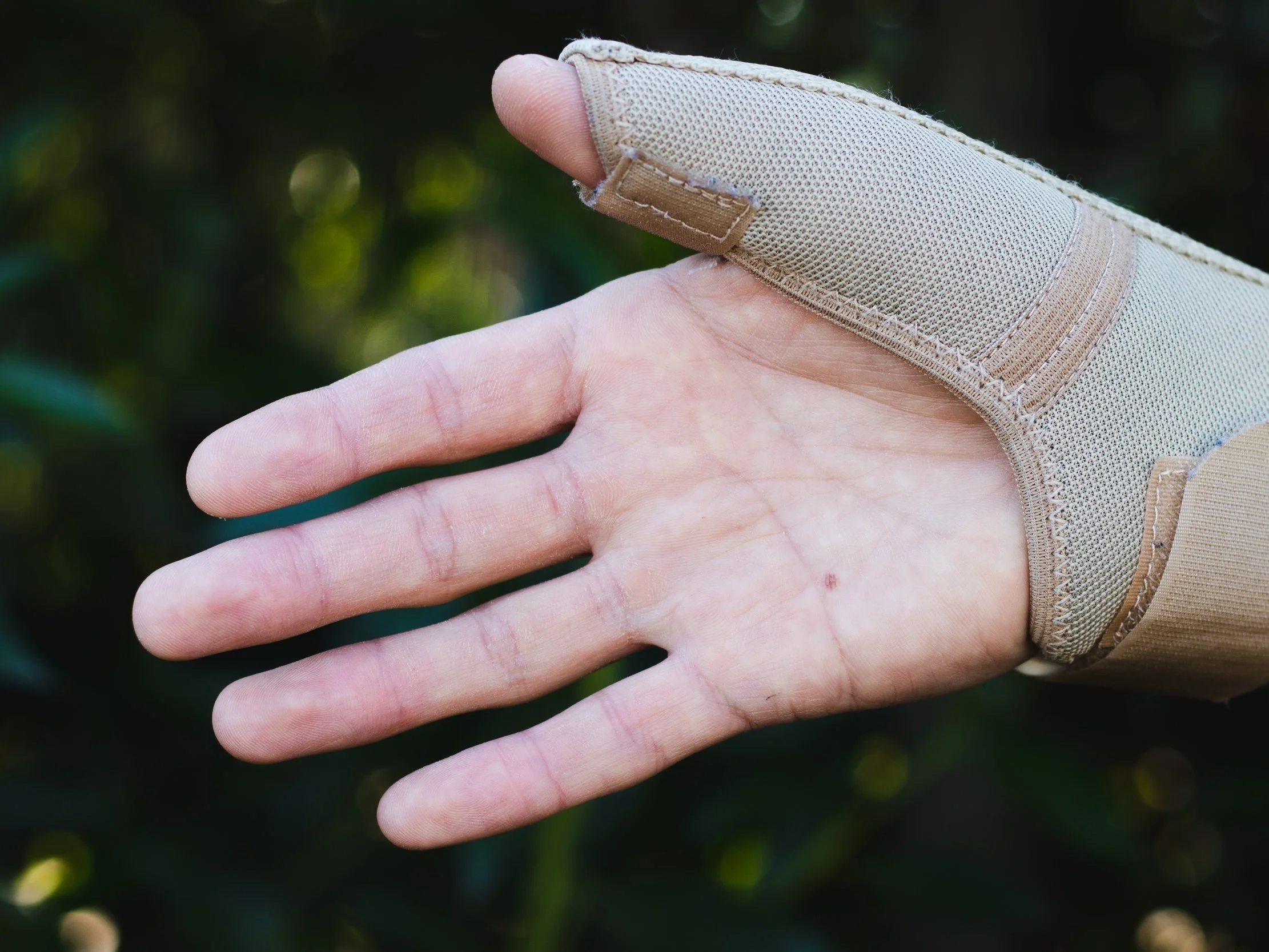 hand wearing a beige thumb brace, holding palm open