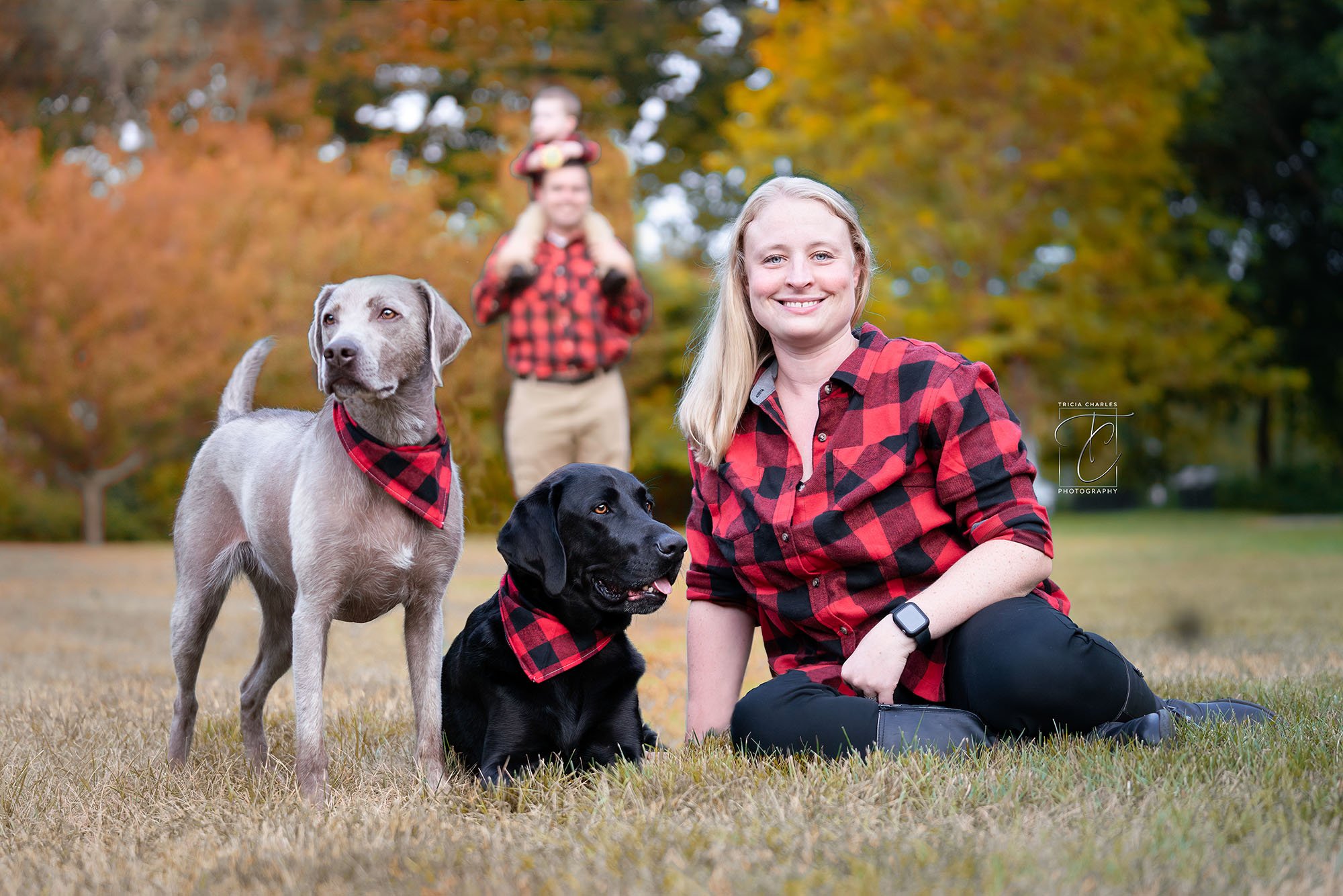 family in red check shirts with 2 labs