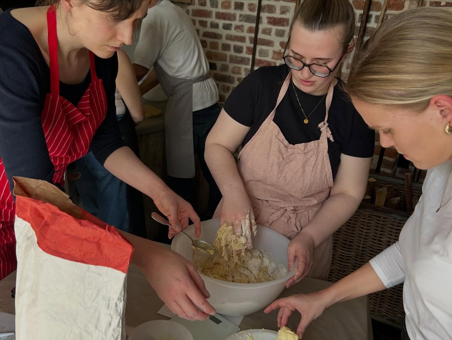 Drie dames werken samen om het perfecte deeg te maken voor hun brood tijdens de workshop bij Bakker Baert
