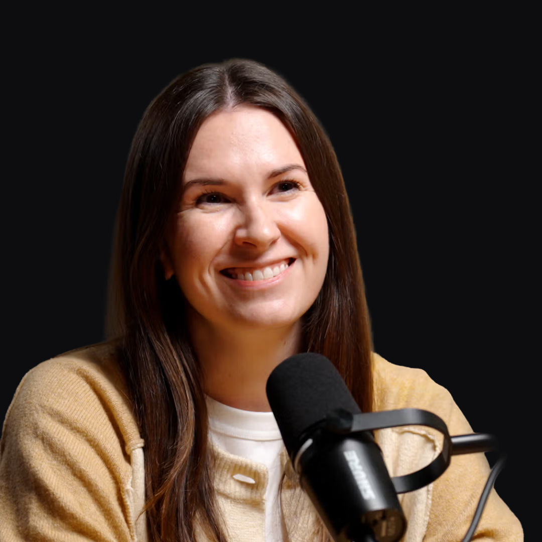 A woman with long brown hair smiling in front of a microphone.