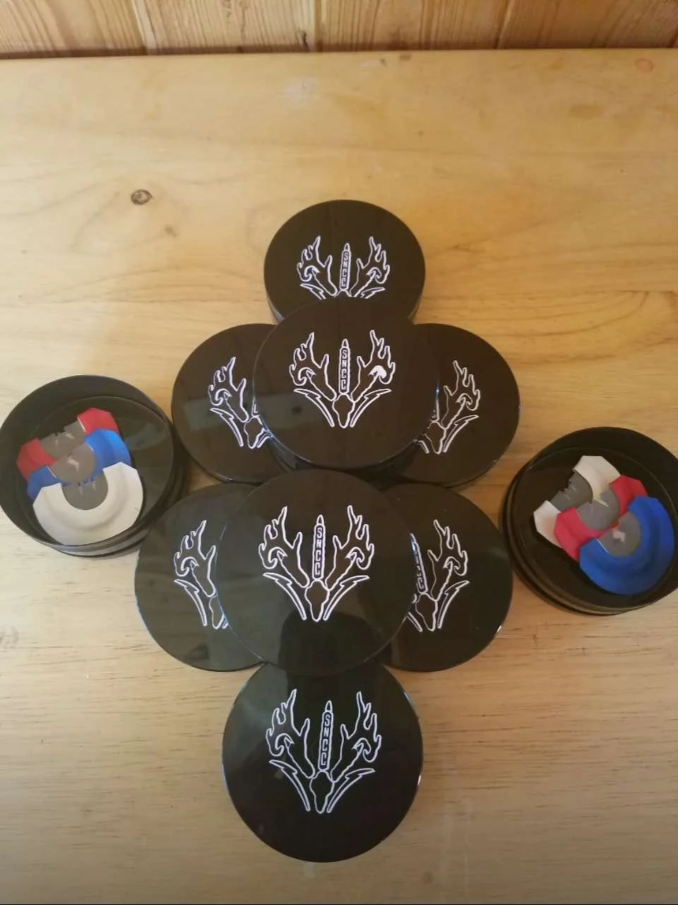 Black hockey pucks with a white logo, with some hockey puck dispensers containing colored hockey puck coasters.