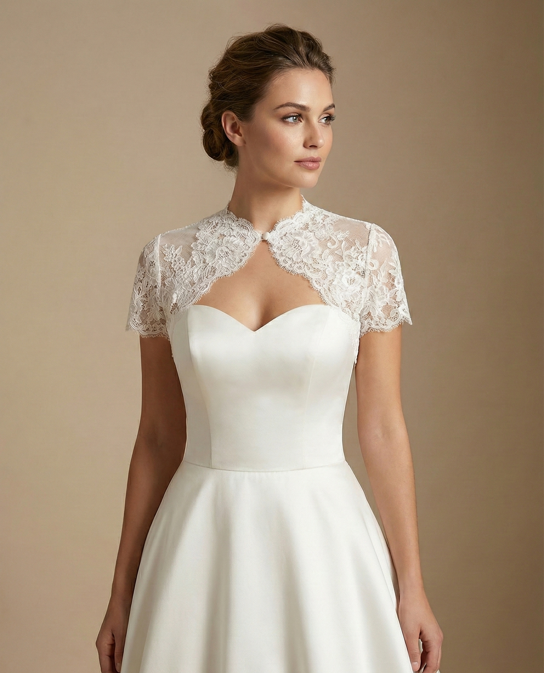 Bride wearing a short-sleeve French lace bridal topper with a keyhole neckline over an ivory satin wedding gown