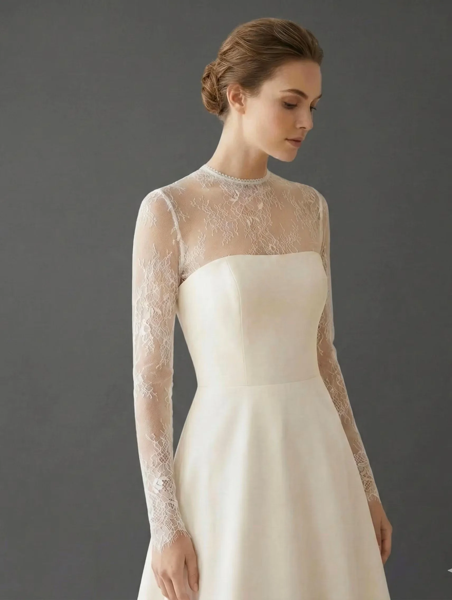 Bride wearing a sheer long-sleeve illusion lace bridal topper over an ivory strapless wedding gown