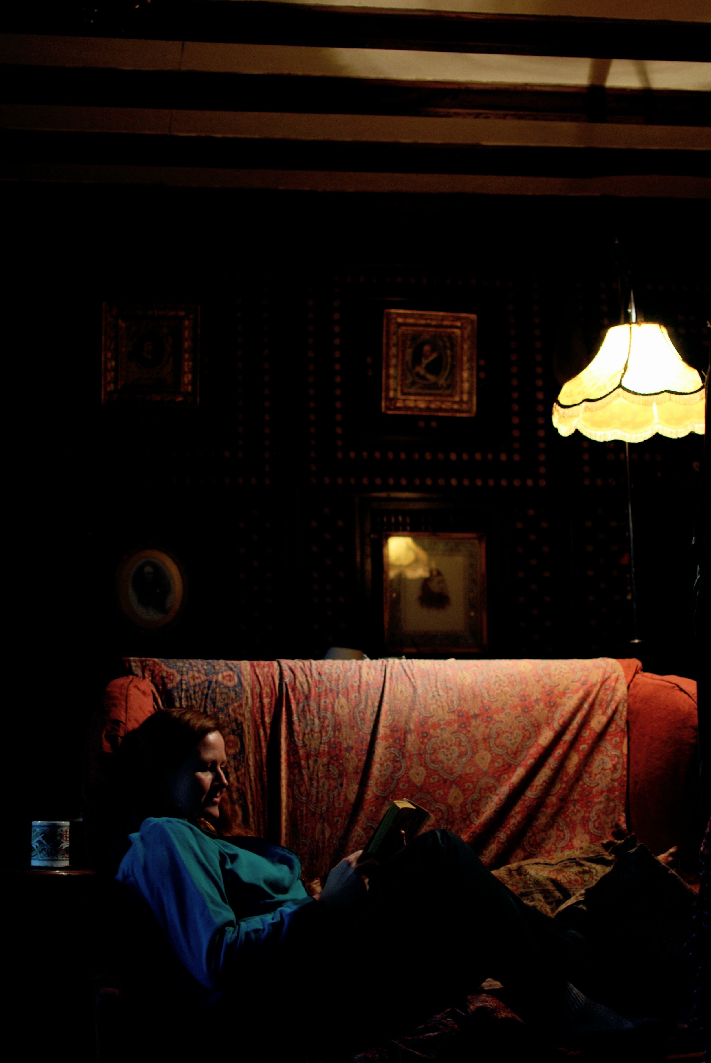 Image of a woman reading by lamplight