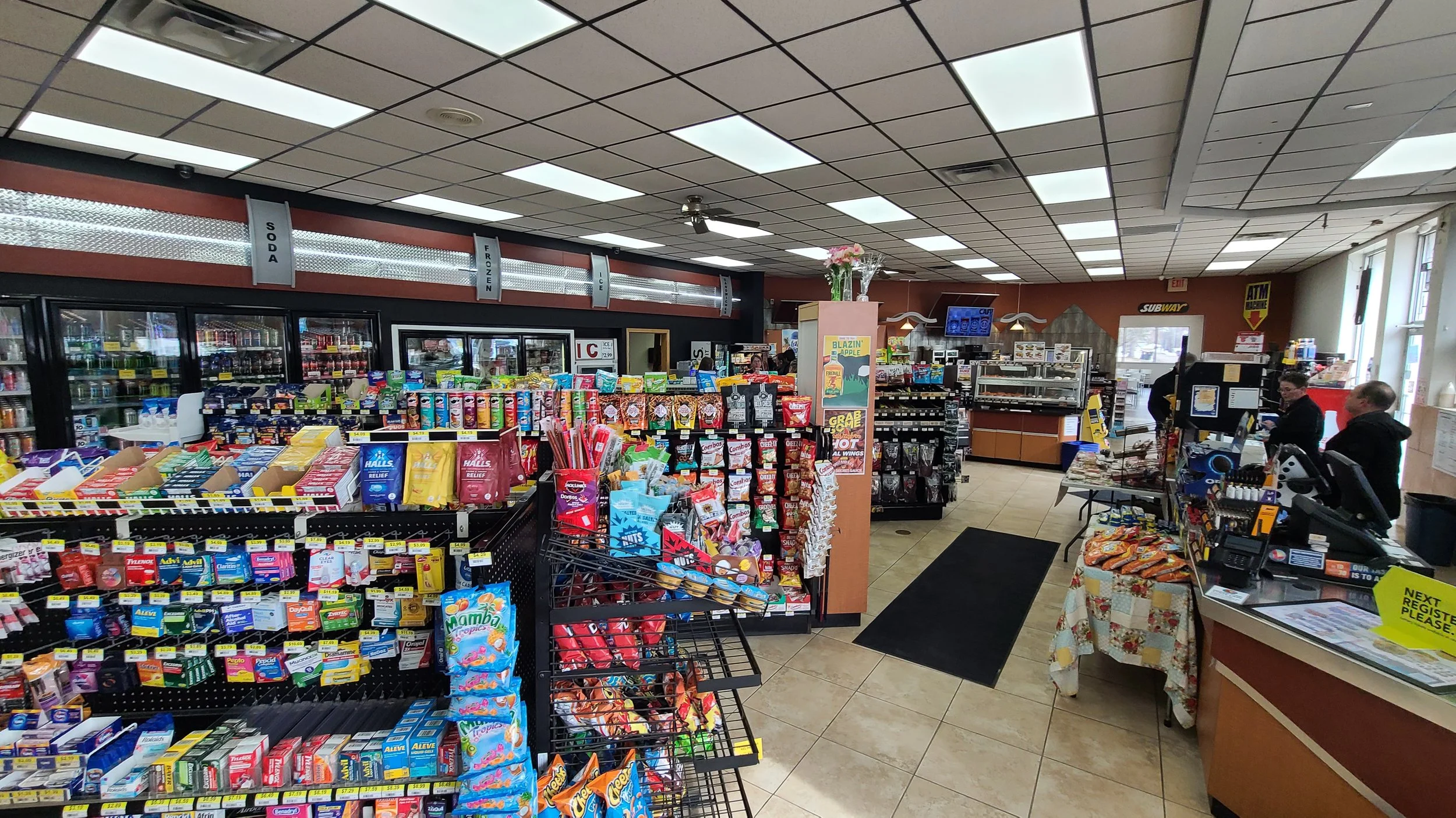 Inside the Fuel On convenience store in Marshfield, Wisconsin, showing aisles of candy and snacks, coolers filled with soda and frozen foods, and a coffee bar at the back.