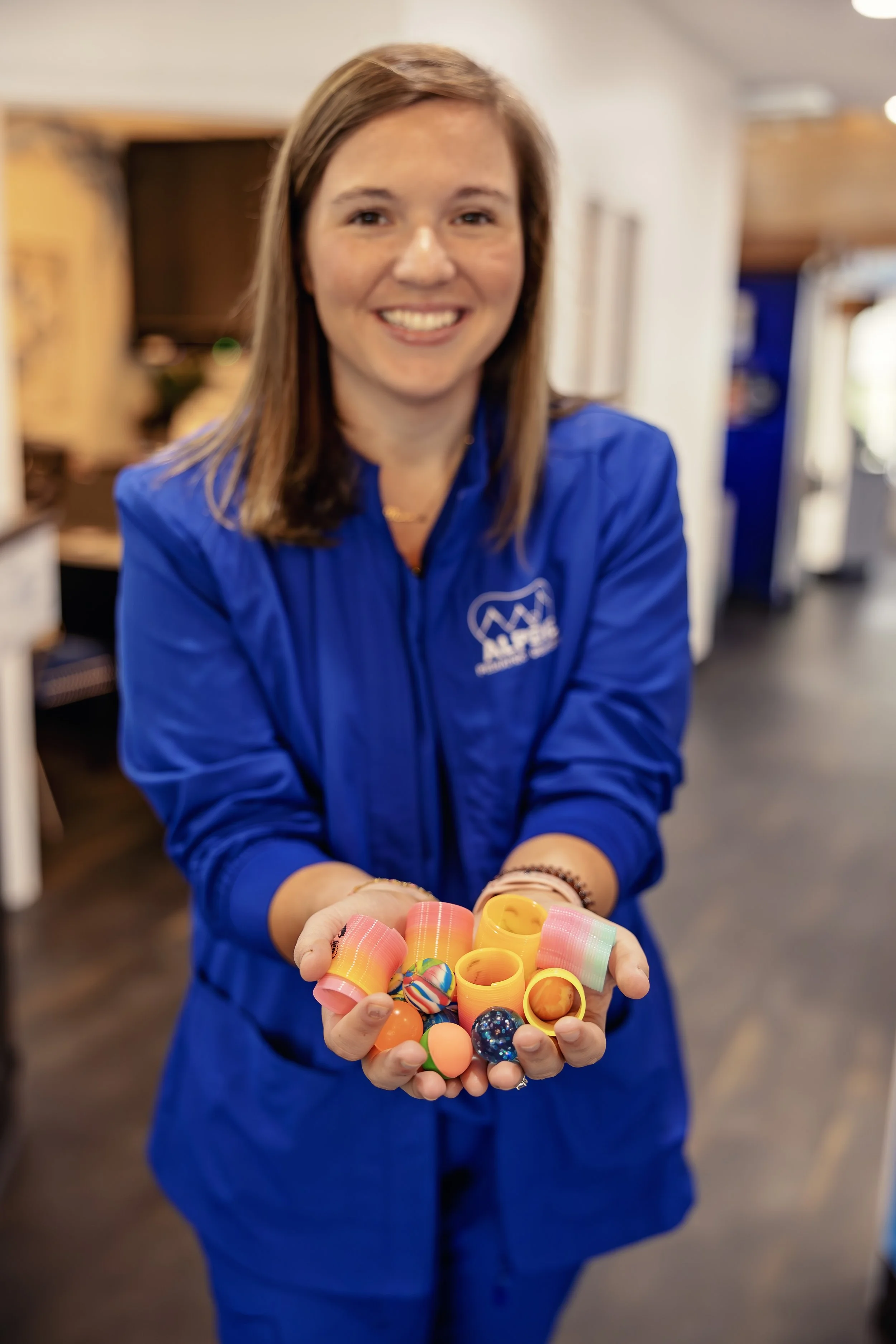 A team member of Alpine Pediatric Dentistry is holding prizes for the patients.