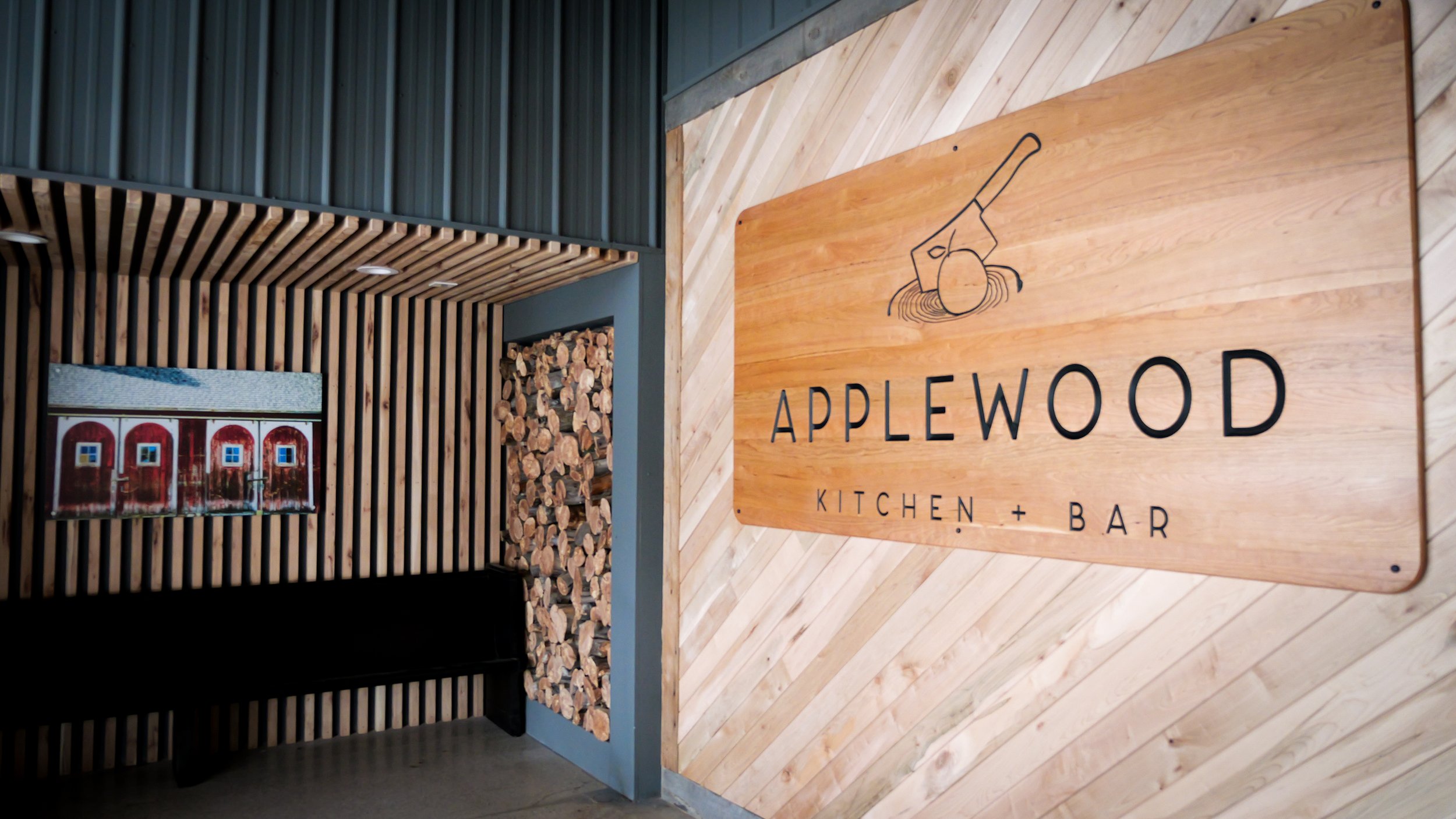Entrance of Applewood Kitchen + Bar with wooden sign and interior decor.