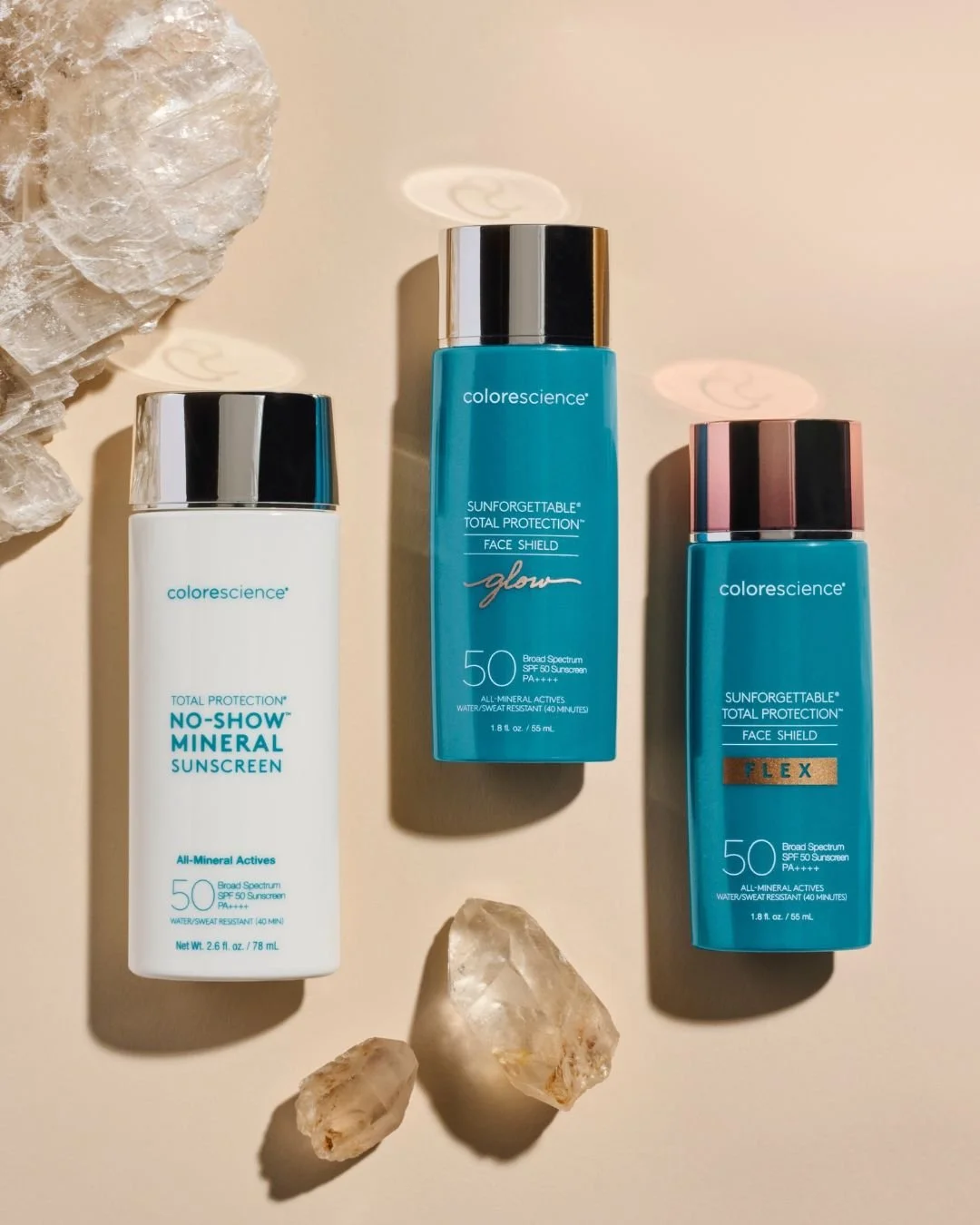 Three bottles of Colorescience sunscreen with crystals around them on a beige background.