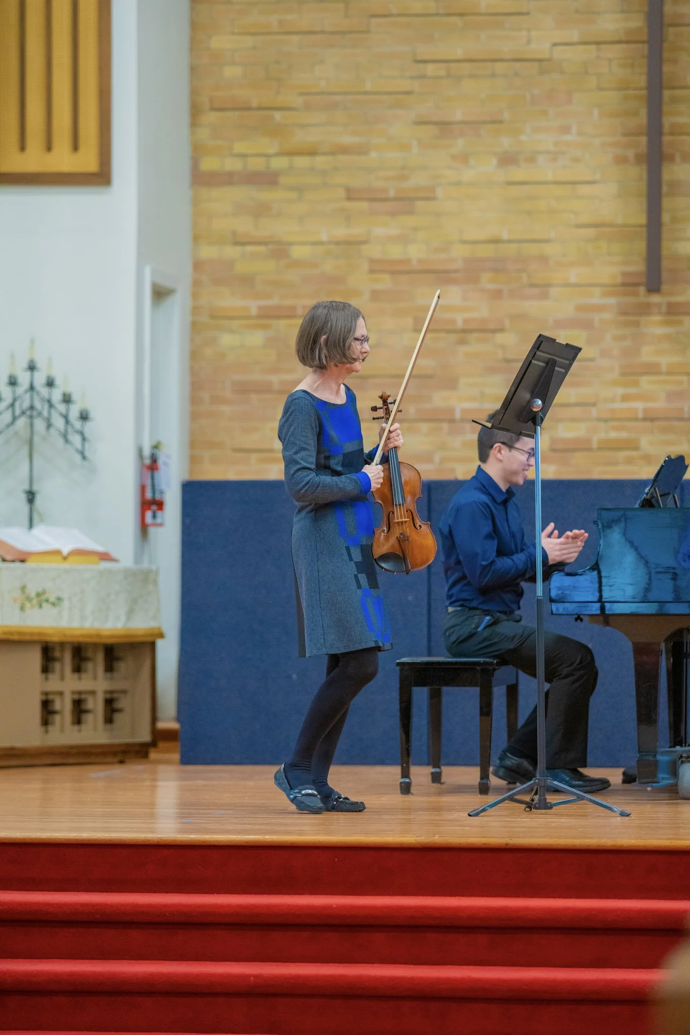 An adult student happily walks off stage after performing