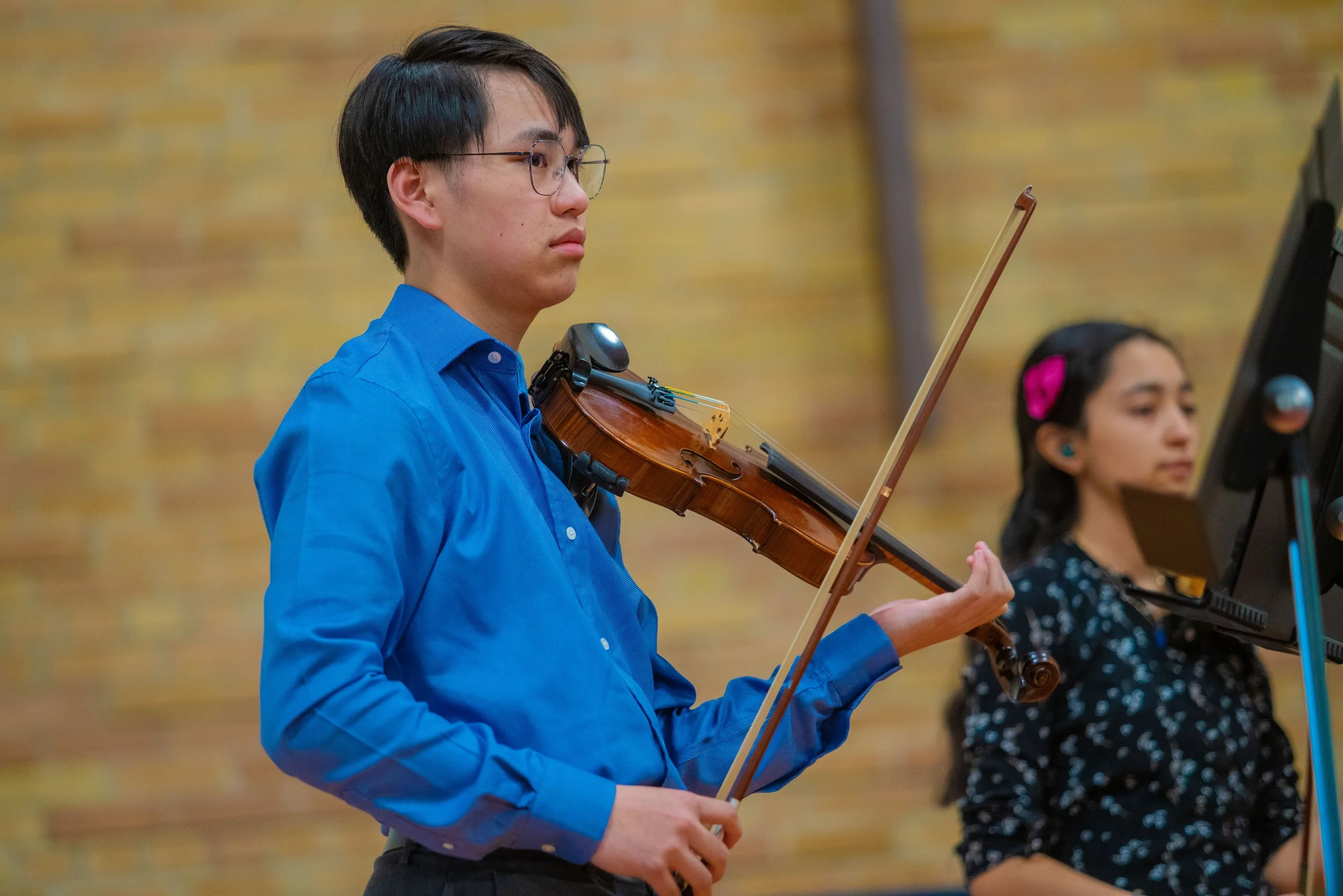 A teenage boy and girl look out at a violin concert