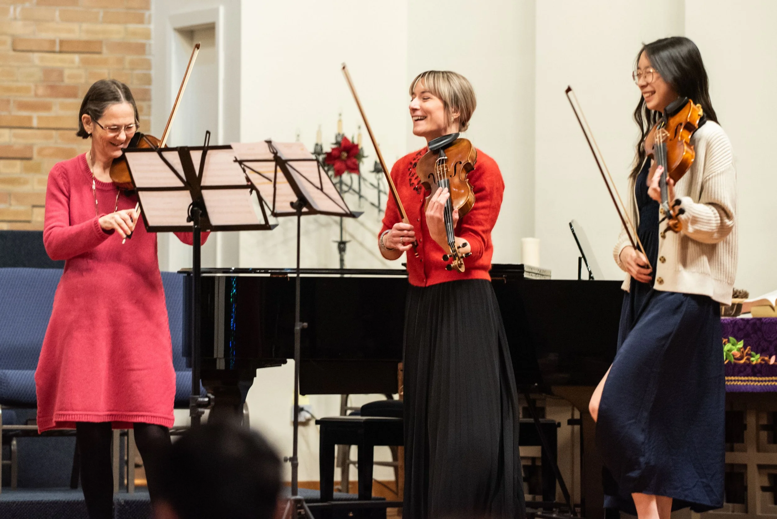 An adult and teenage violin student smile happily on stage after performing with Carmen