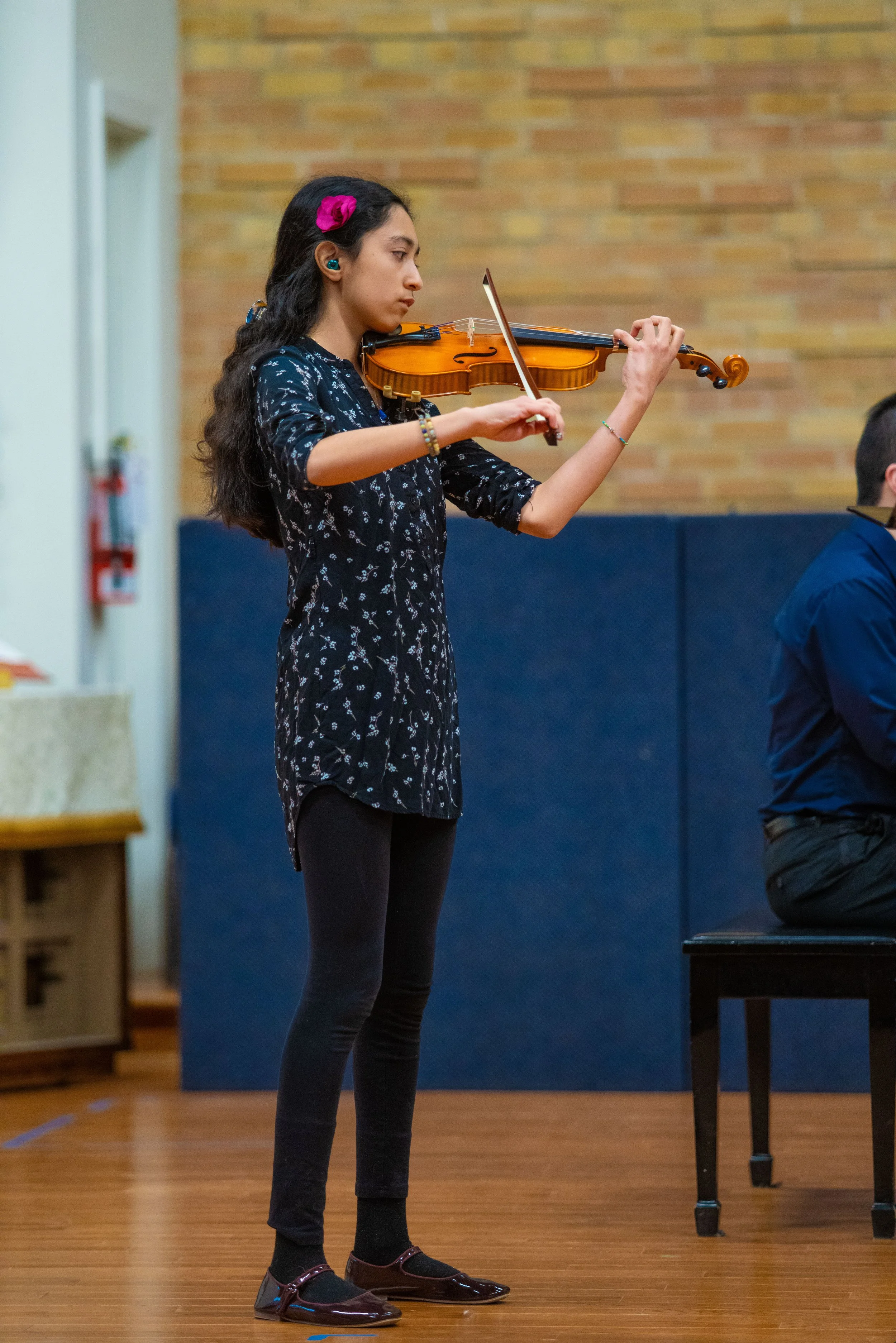A teenage girl plays violin on stage at a recital
