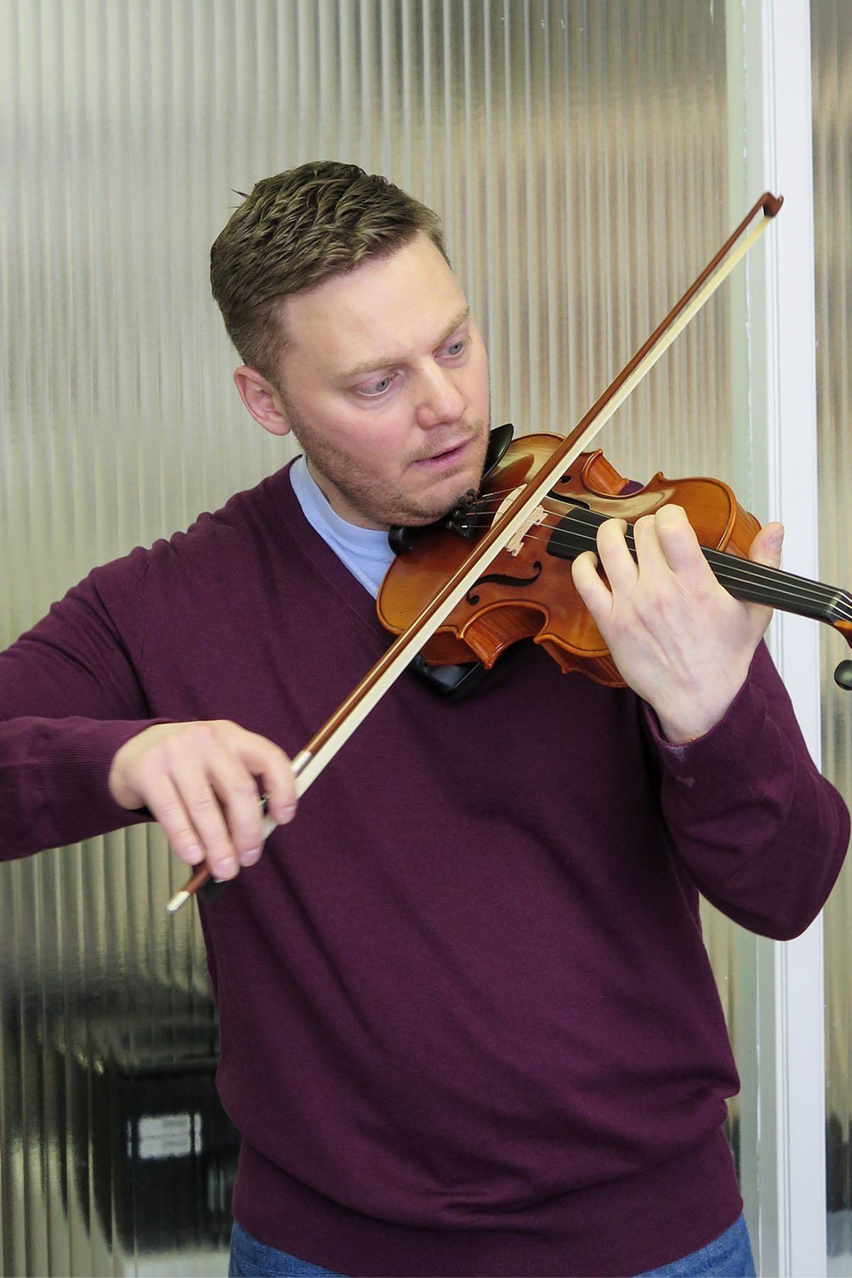 An adult man plays violin with focus during a lesson