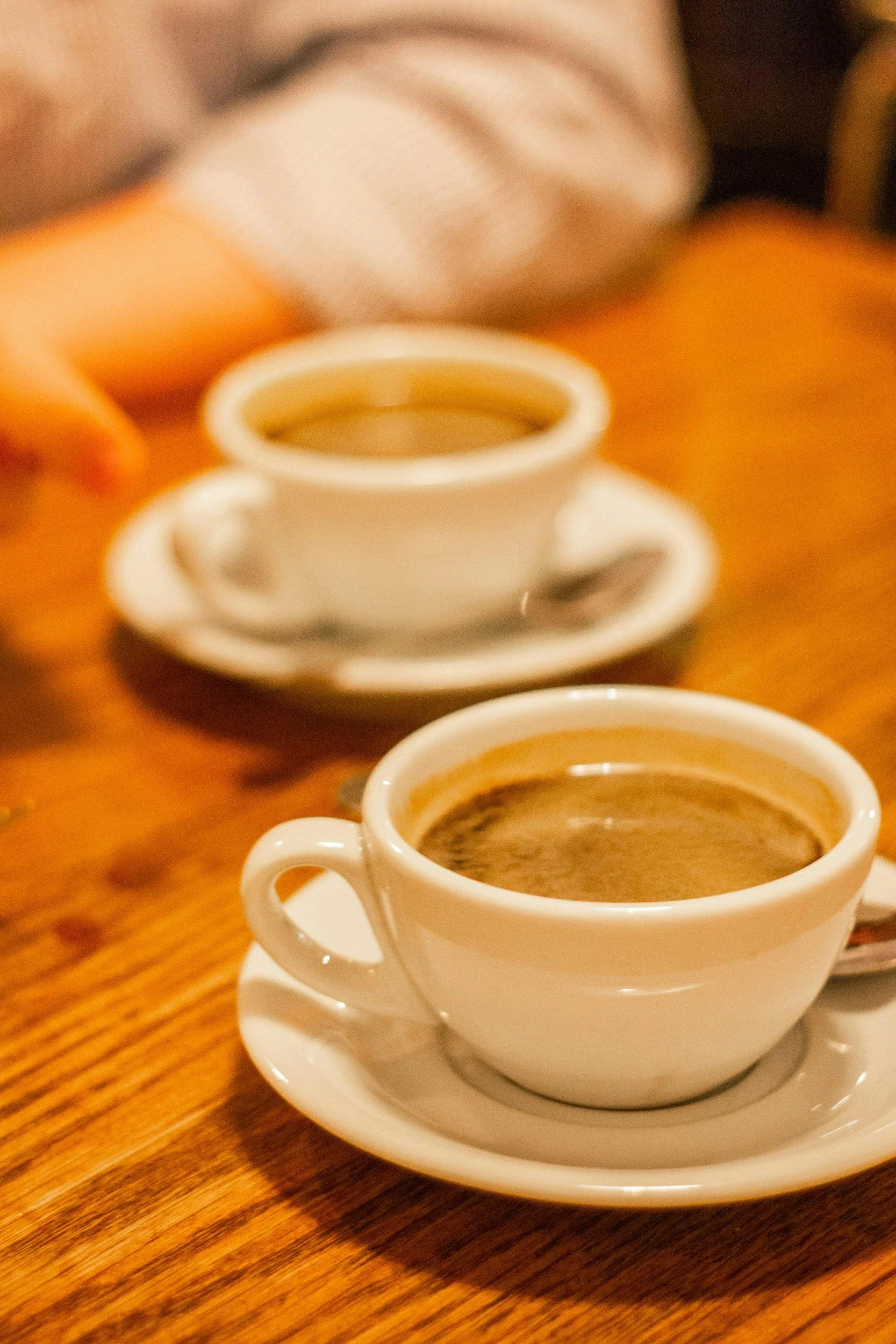 A cup of coffee on a wooden table representing a relaxed 1:1 leadership coaching discovery call with Curious Leadership