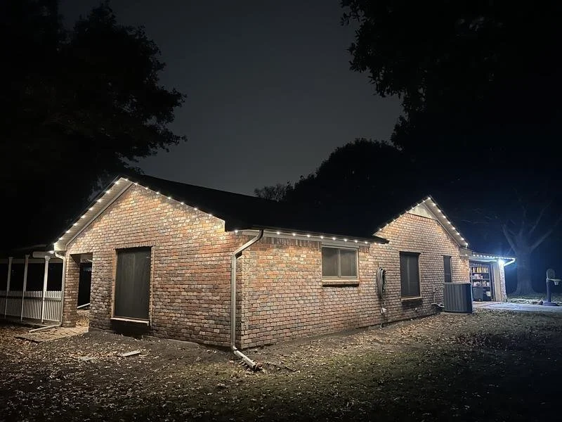 A brick house decorated with white string lights at night