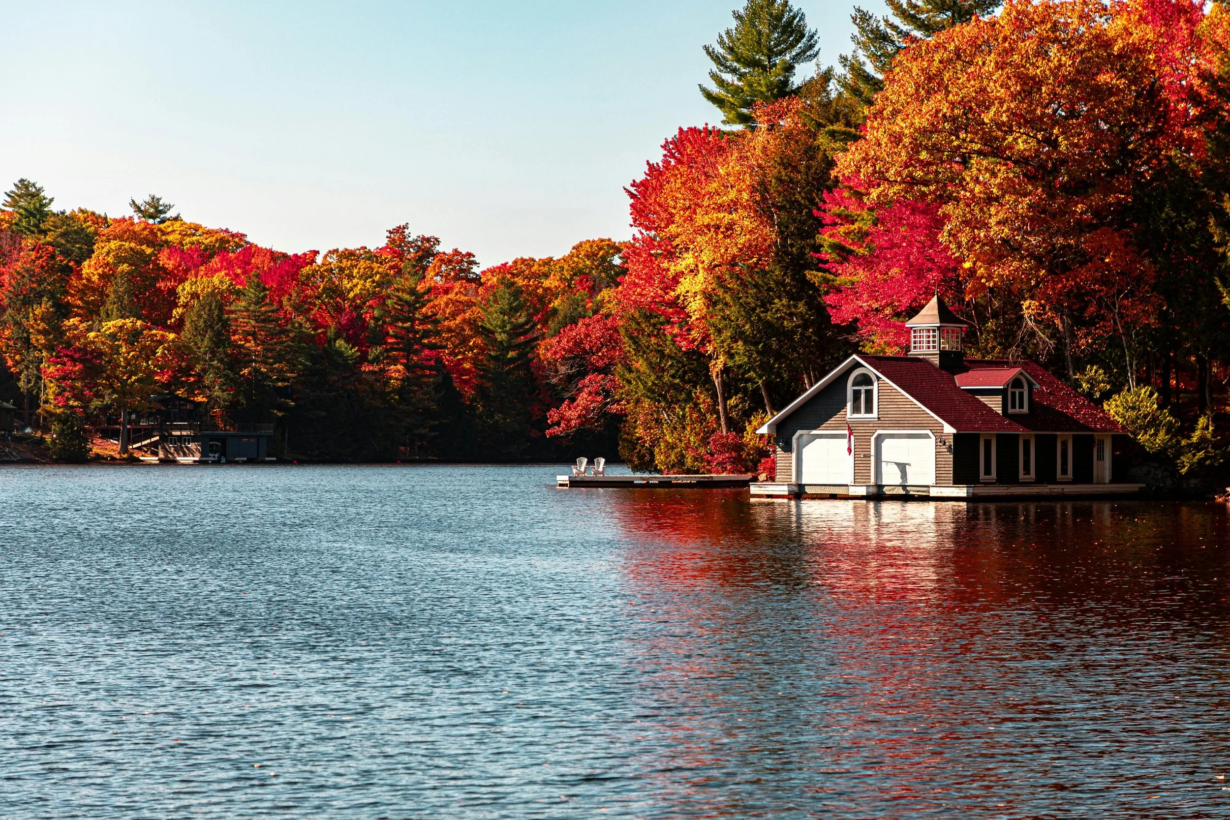 View of Musoka Lake, a cottage on the lake and autumn colour maple leaves
